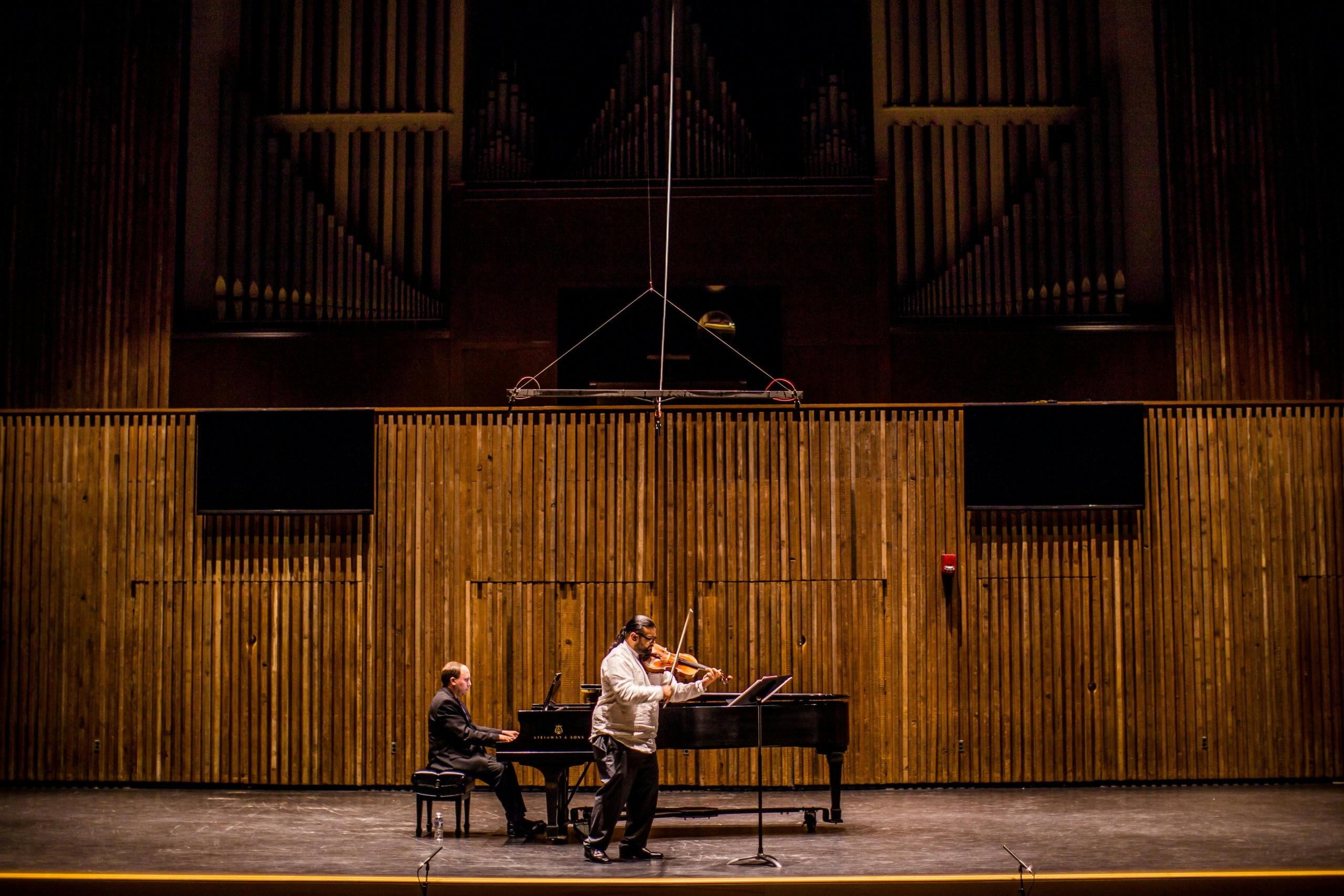 Imagen de un concierto de un hombre tocando el piano y otro tocando el violin