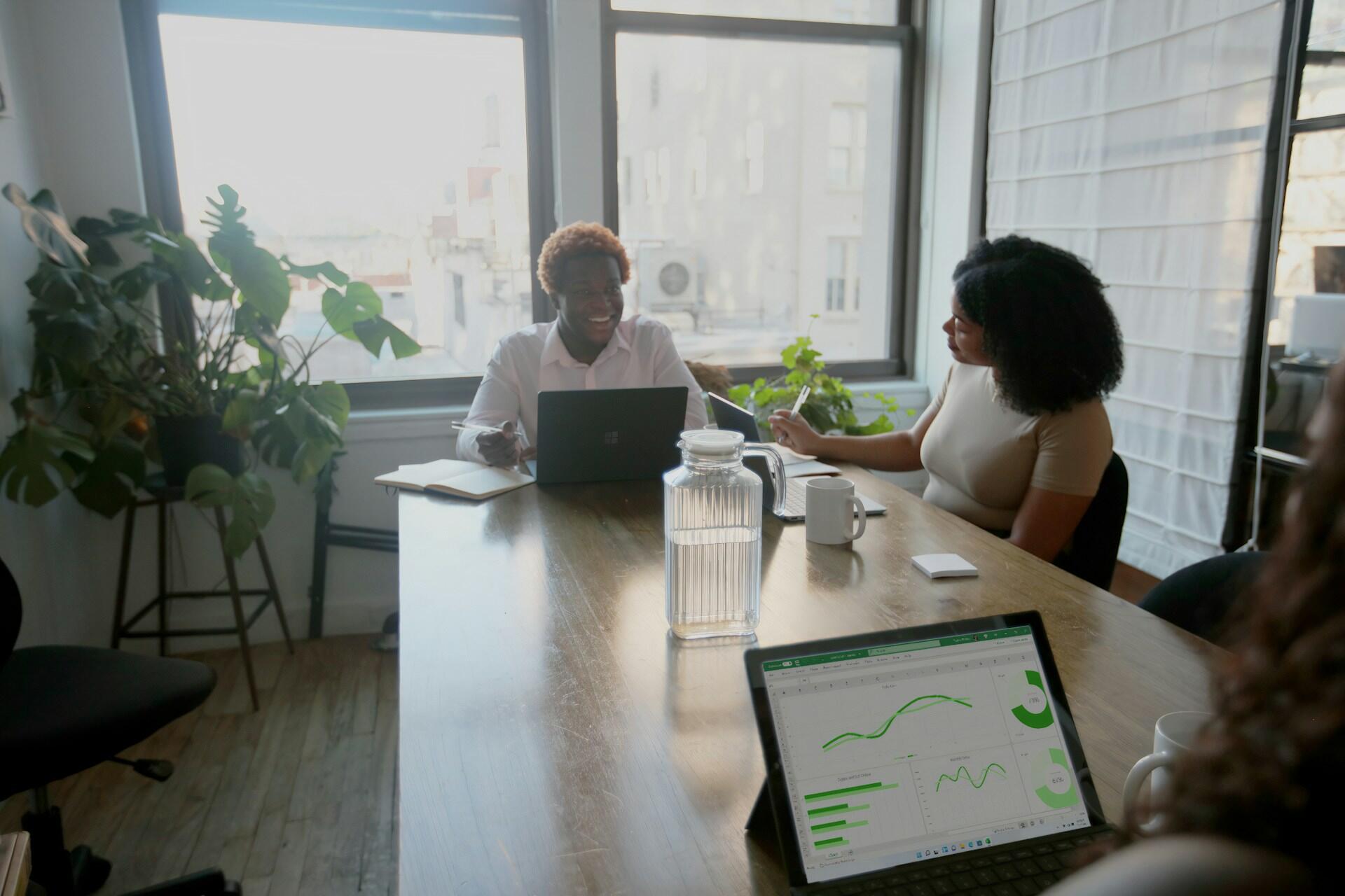 Tres personas en una mesa de trabajo con su portátil de Microsoft