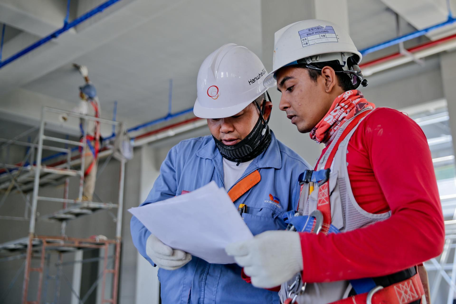 Dos contructores de obras revisando las solicitudes de materiales