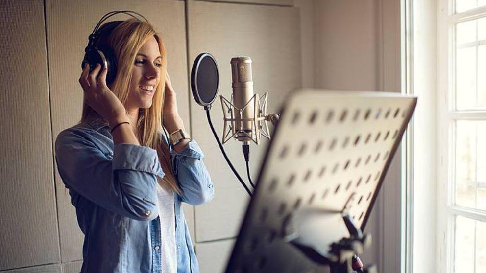 Mujer frente al micrófono en sala de grabación