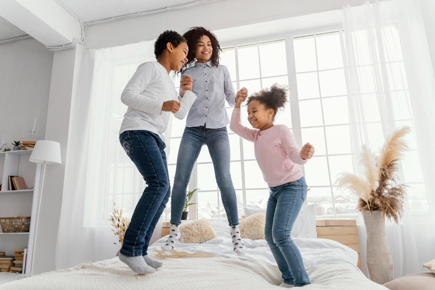 Madre bailando con sus dos hijos sobre la cama
