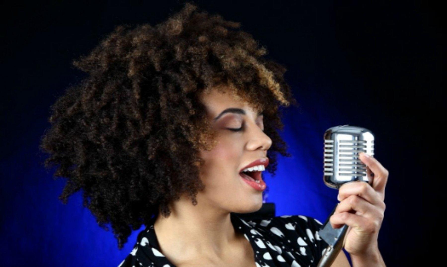 Chica de pelo ondulado cantando.