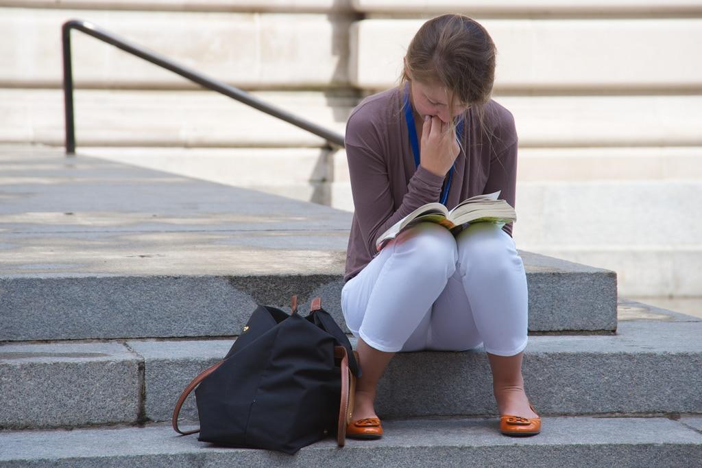 Una alumna estudiando en una escalera.