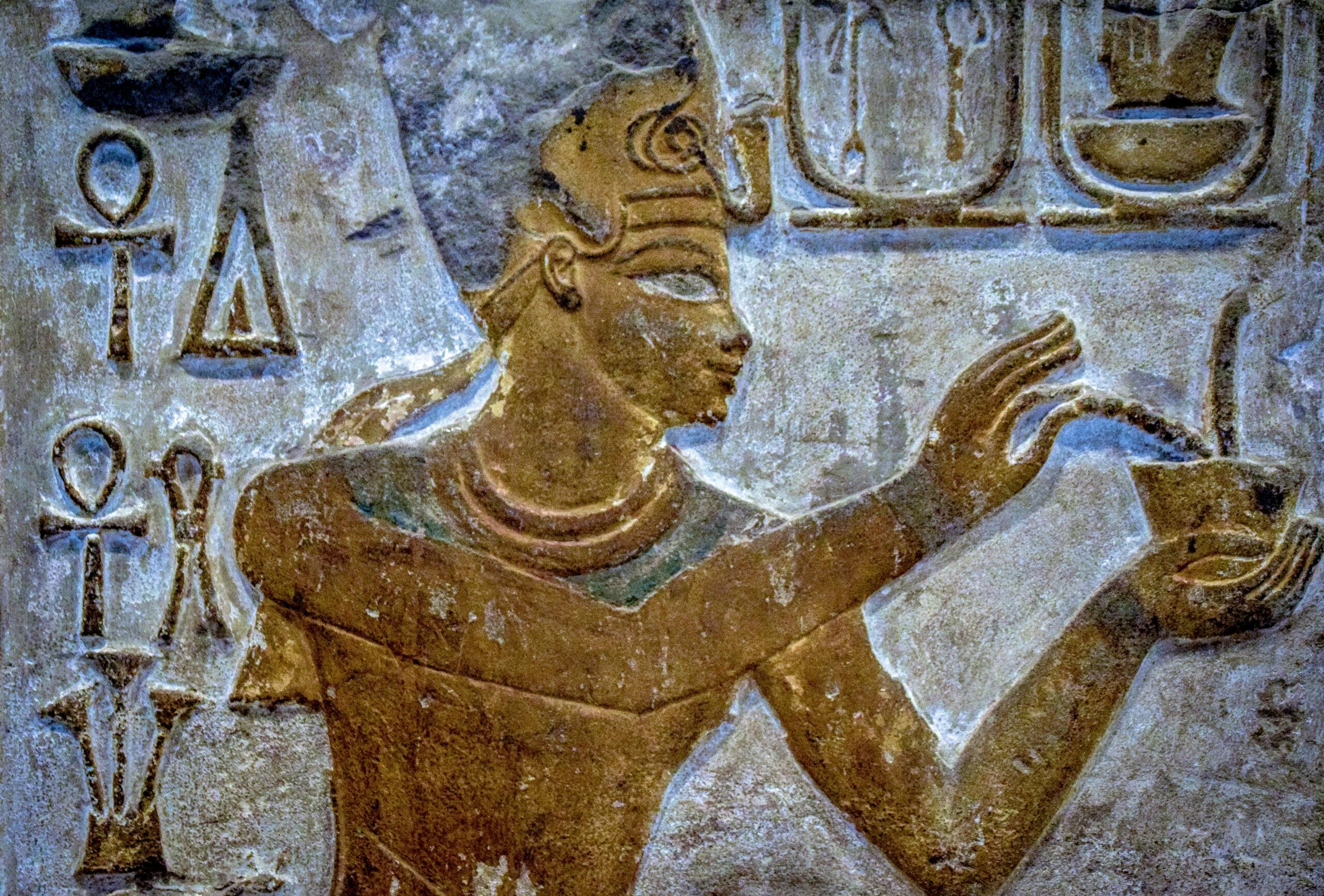 Starověký egyptský reliéf s postavou faraona a hieroglyfy vytesanými do kamene
