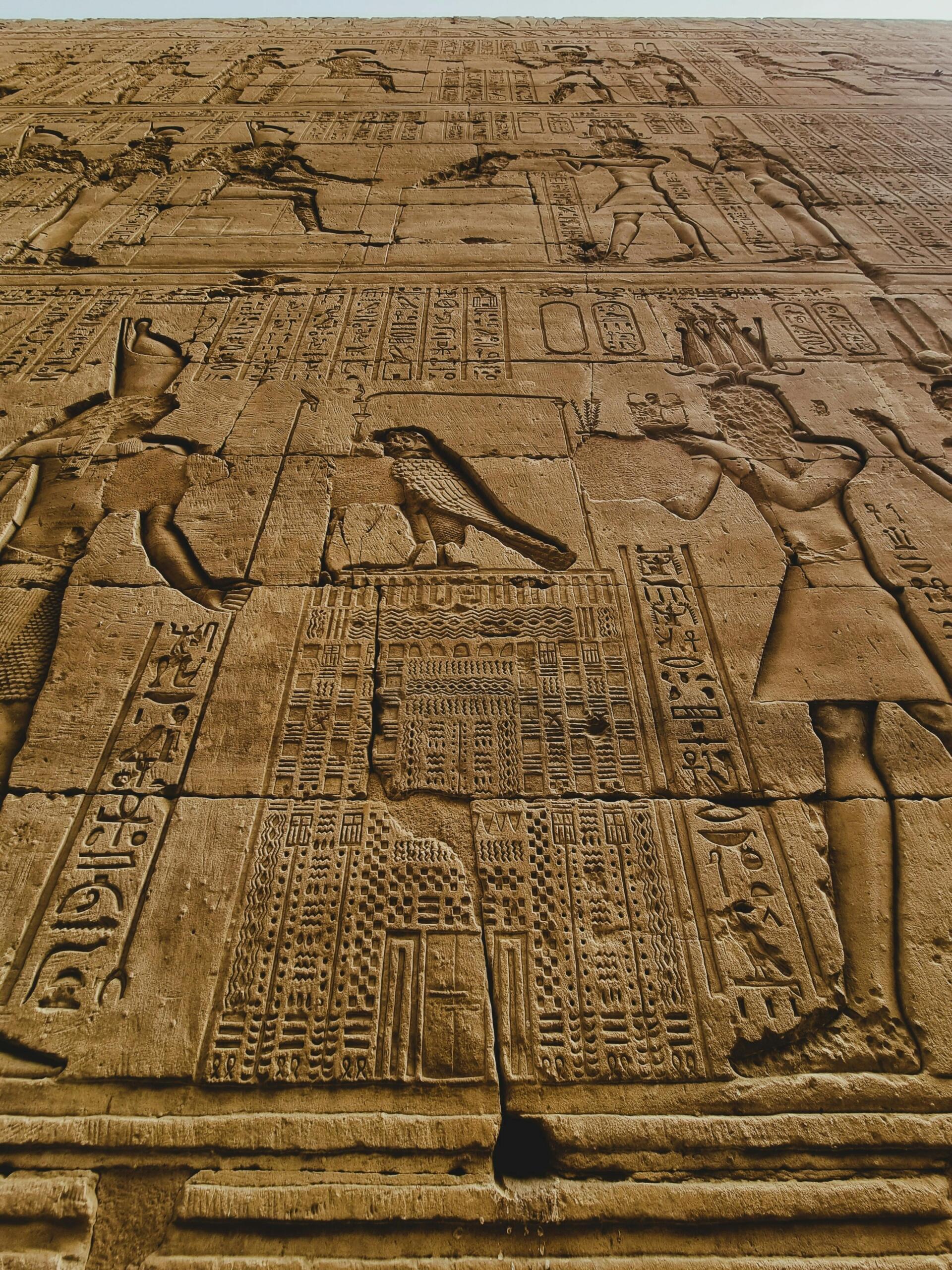 Starověké egyptské hieroglyfy vytesané do kamenné chrámové zdi.