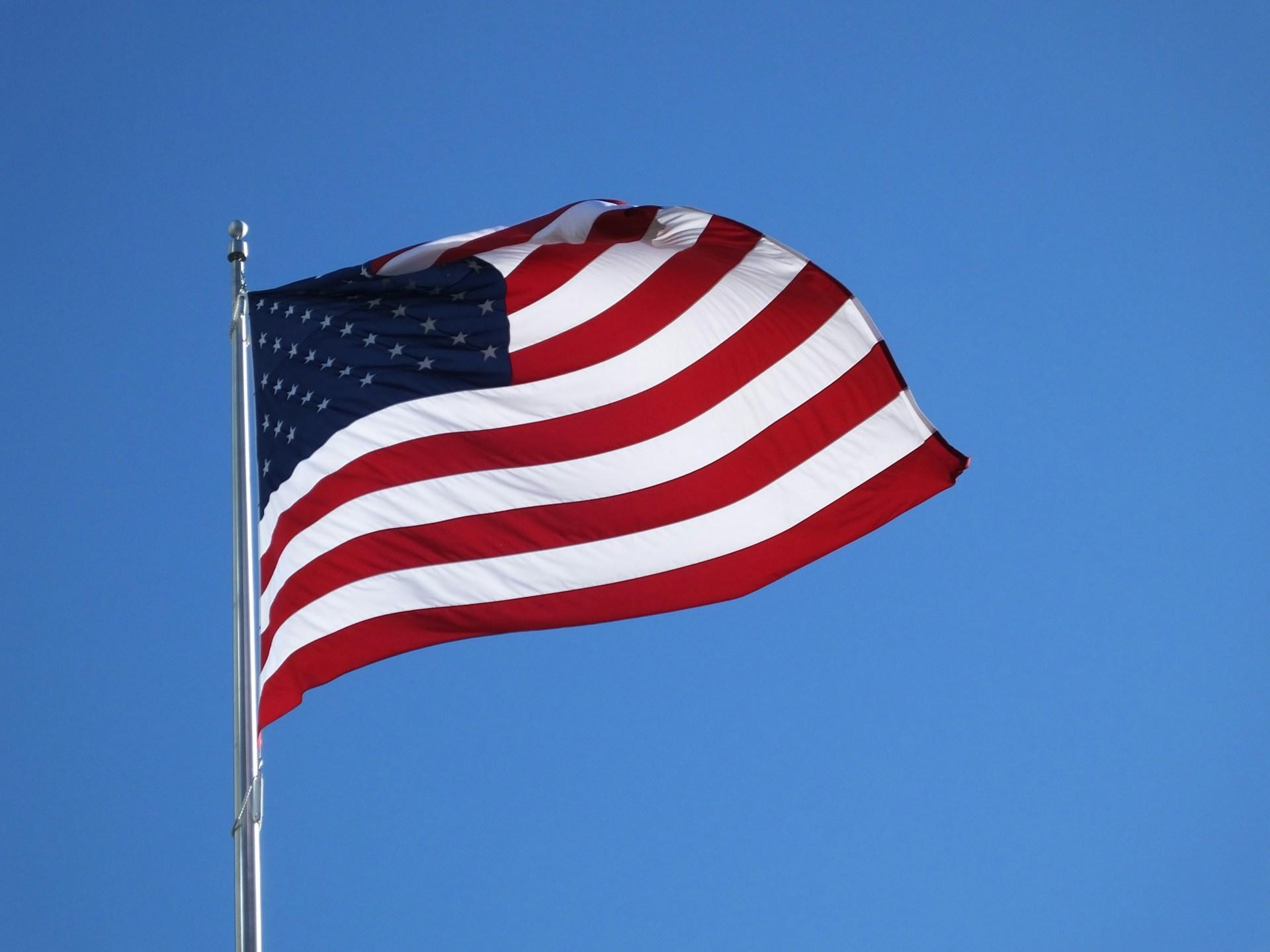 Die Flagge der USA weht vor blauem Himmel im Wind