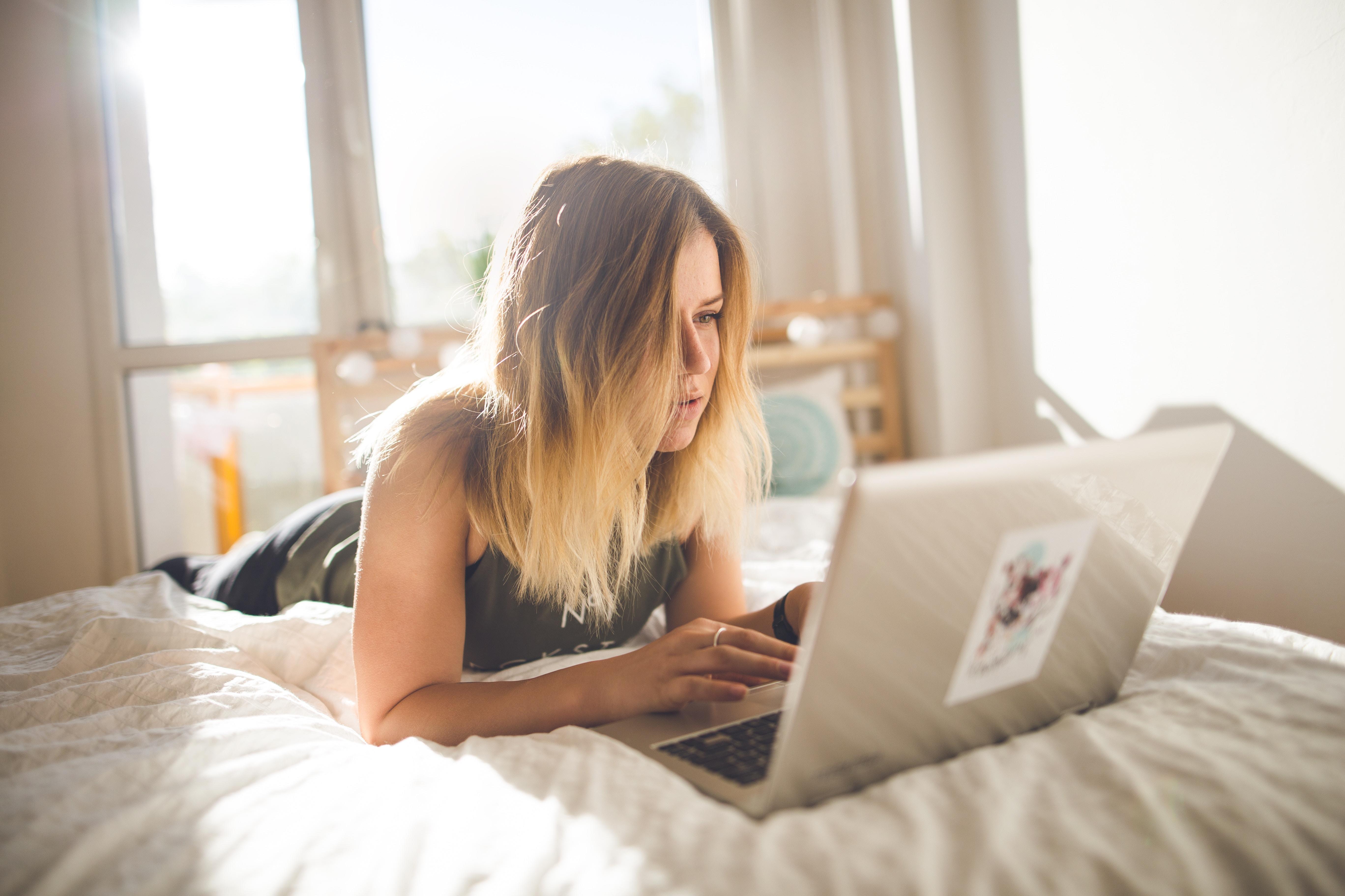 Frau liegt auf Bett mit Laptop