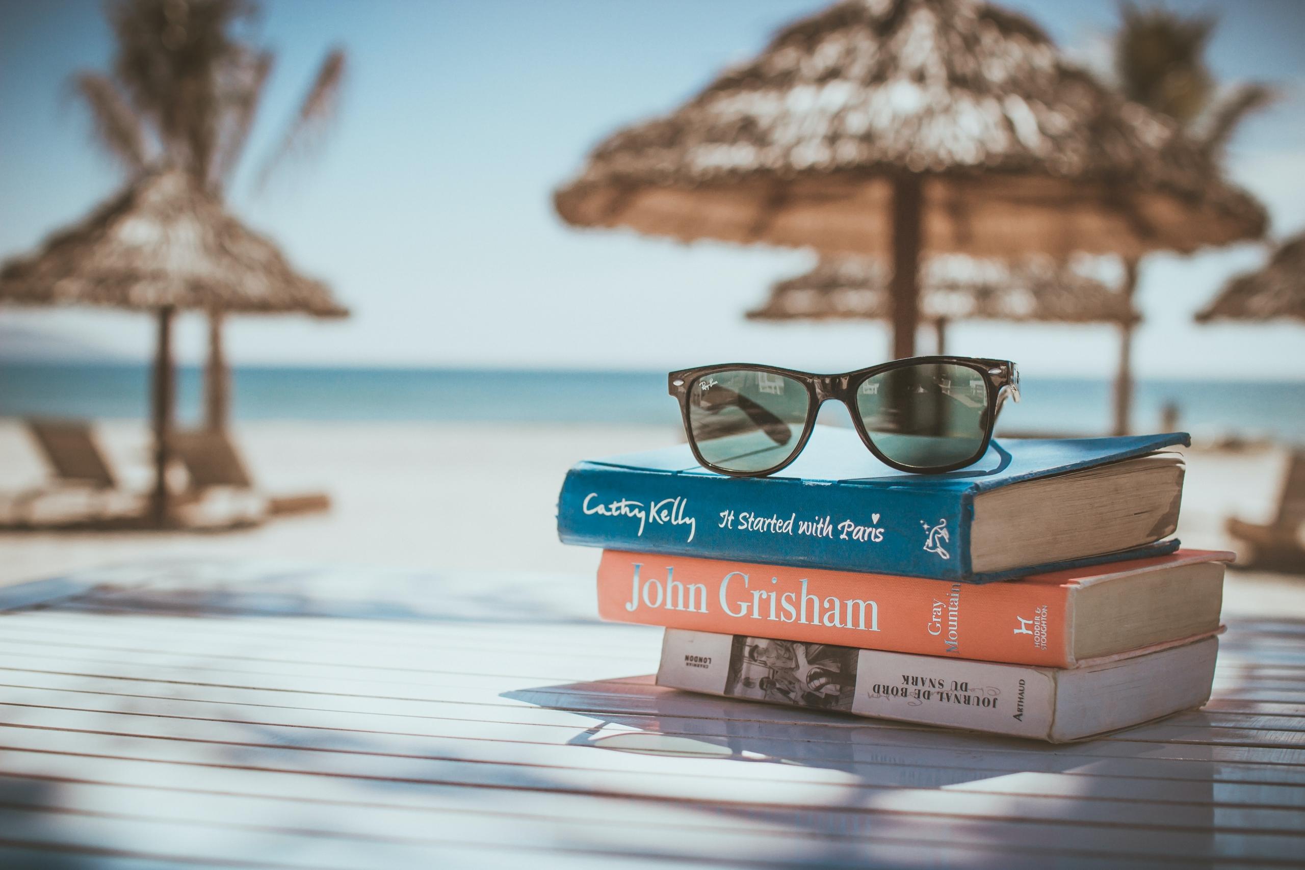 Mehrere Bücher übereinander am Strand.