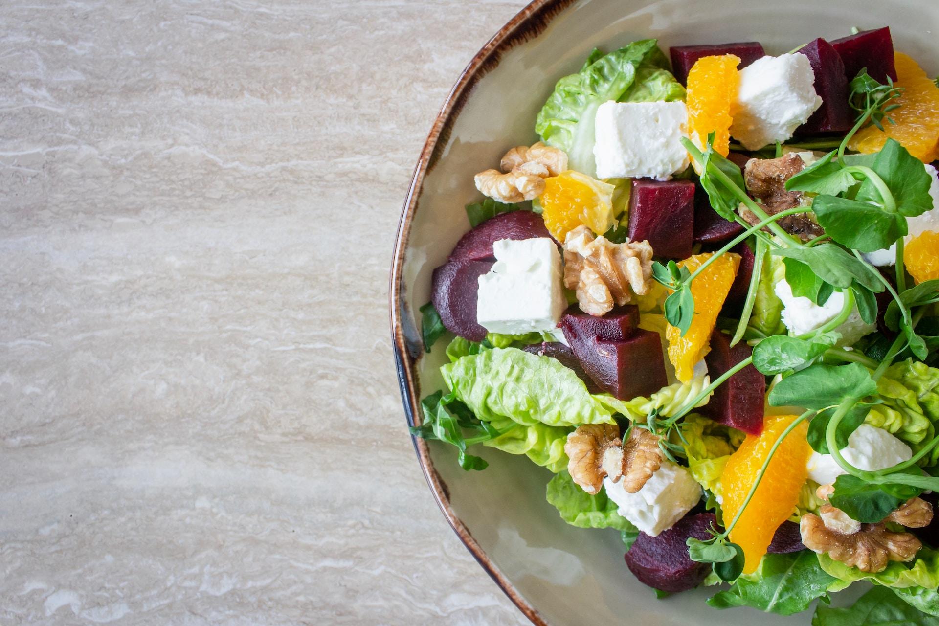 Eine Schale auf einem Tisch mit grünem Salat und Rote Beete und Nüssen und Feta finden alle Sportfans lecker.