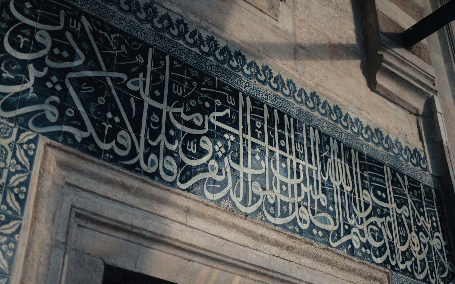 Wand mit weißer Schrift auf dunklem Hintergrund über Türbogen.