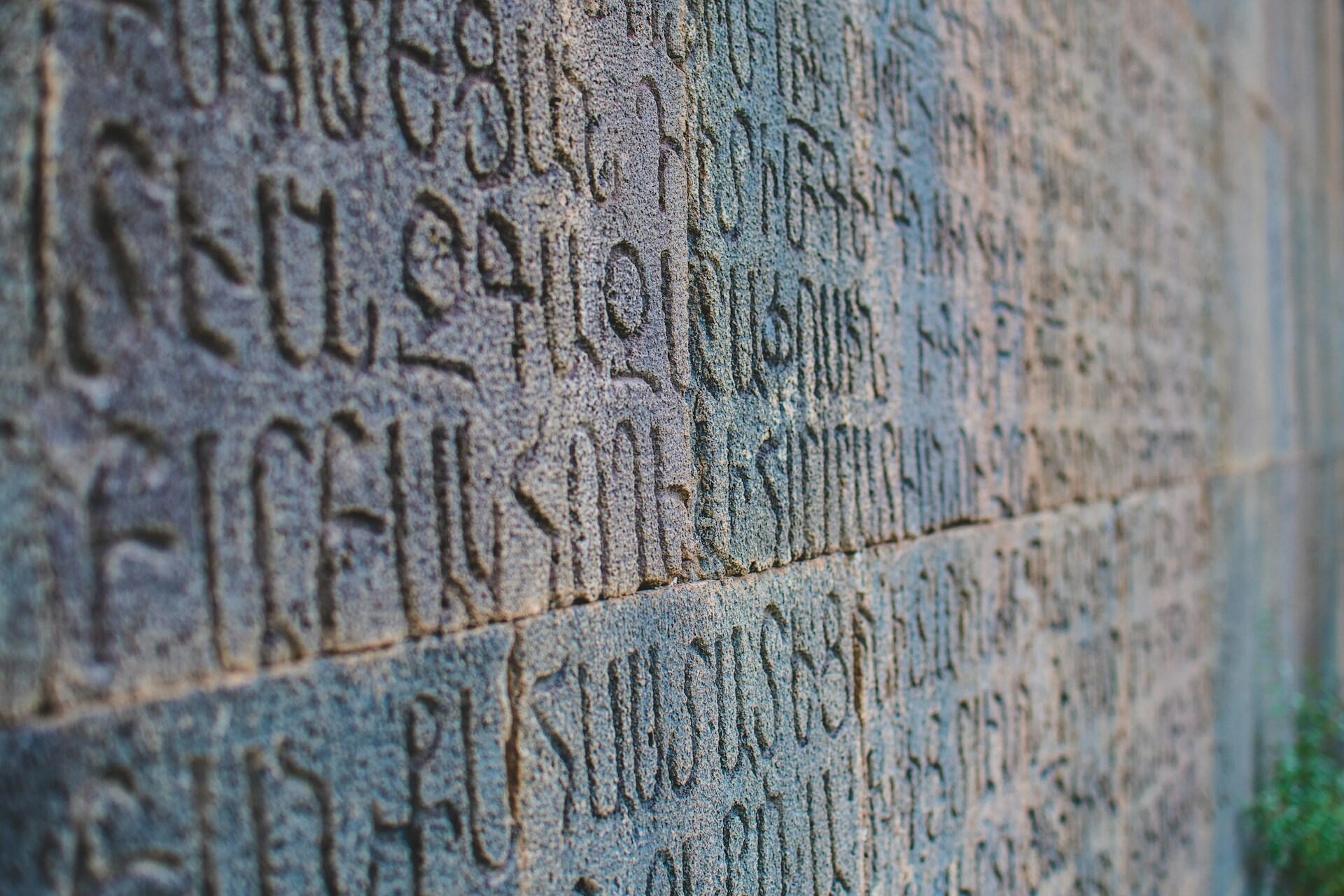 Schriftzeichen auf steinerner Mauer.