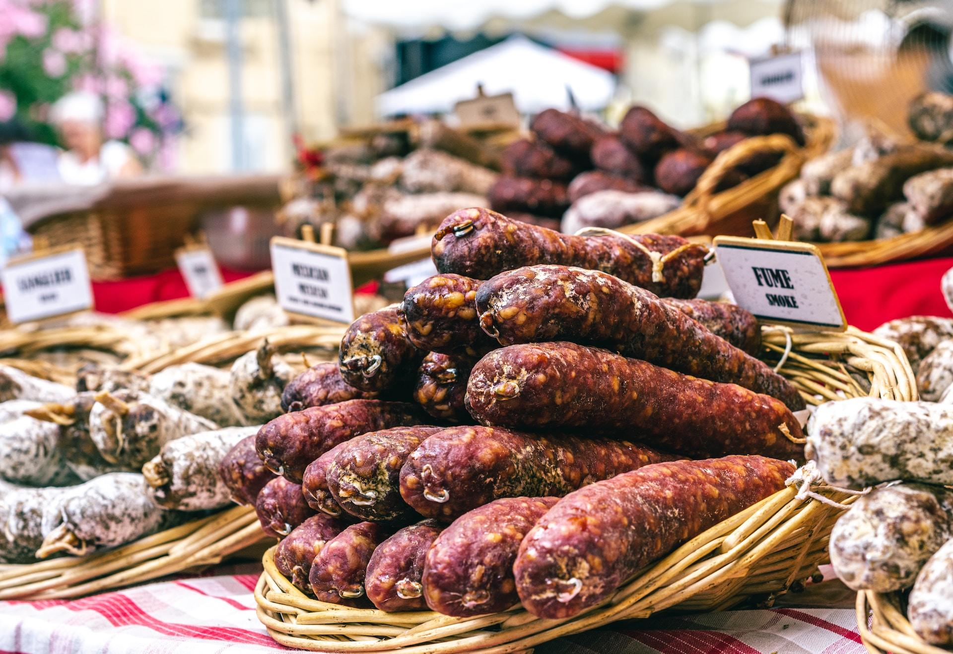 Verschiedene Würste auf einem französischen Marktstand aufgeschichtet.