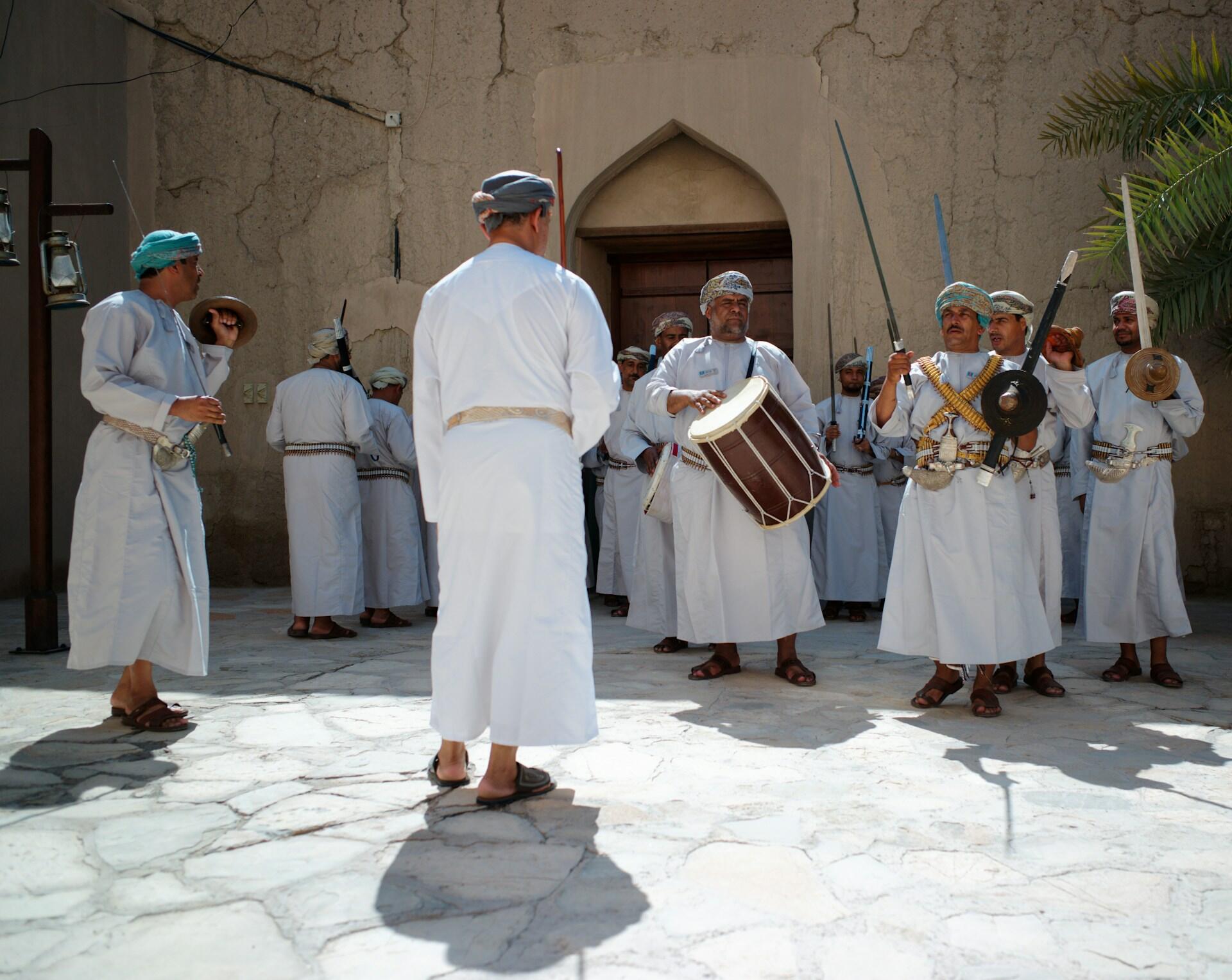 Gruppe Männer in weißen Gewändern mit Musikinstrumenten in Hof.