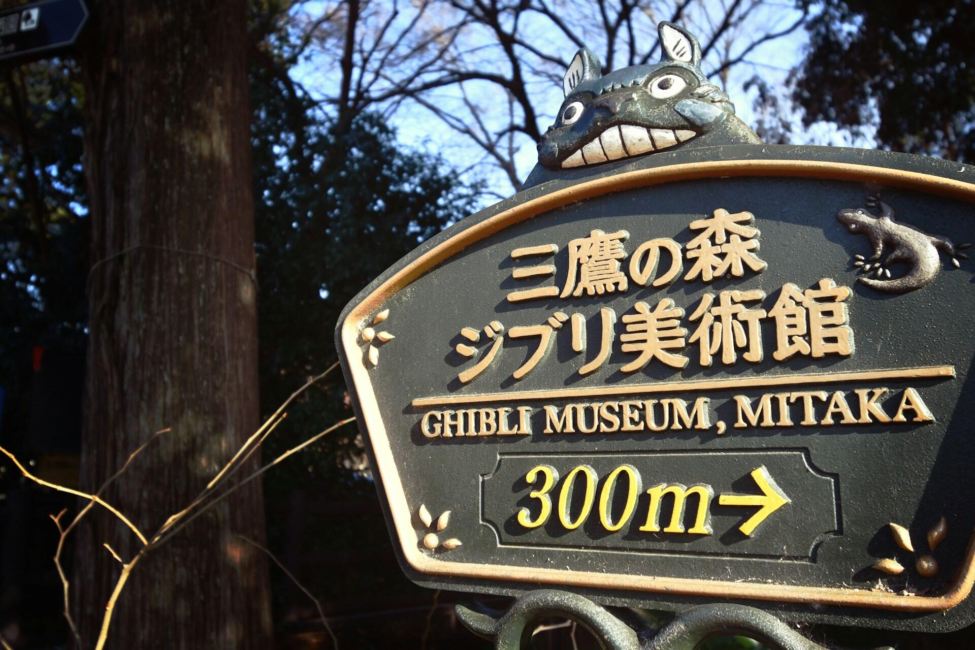 Schild mit japanischer Schrift neben Baum.