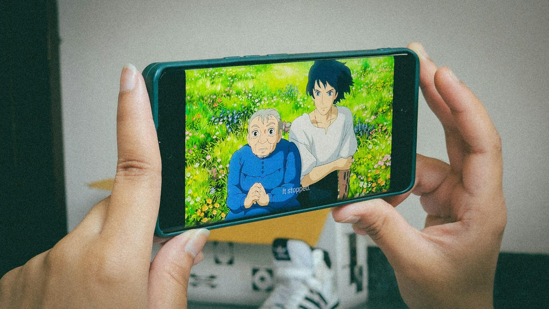 Person hält Handy mit Zeichentrickfilm drauf.