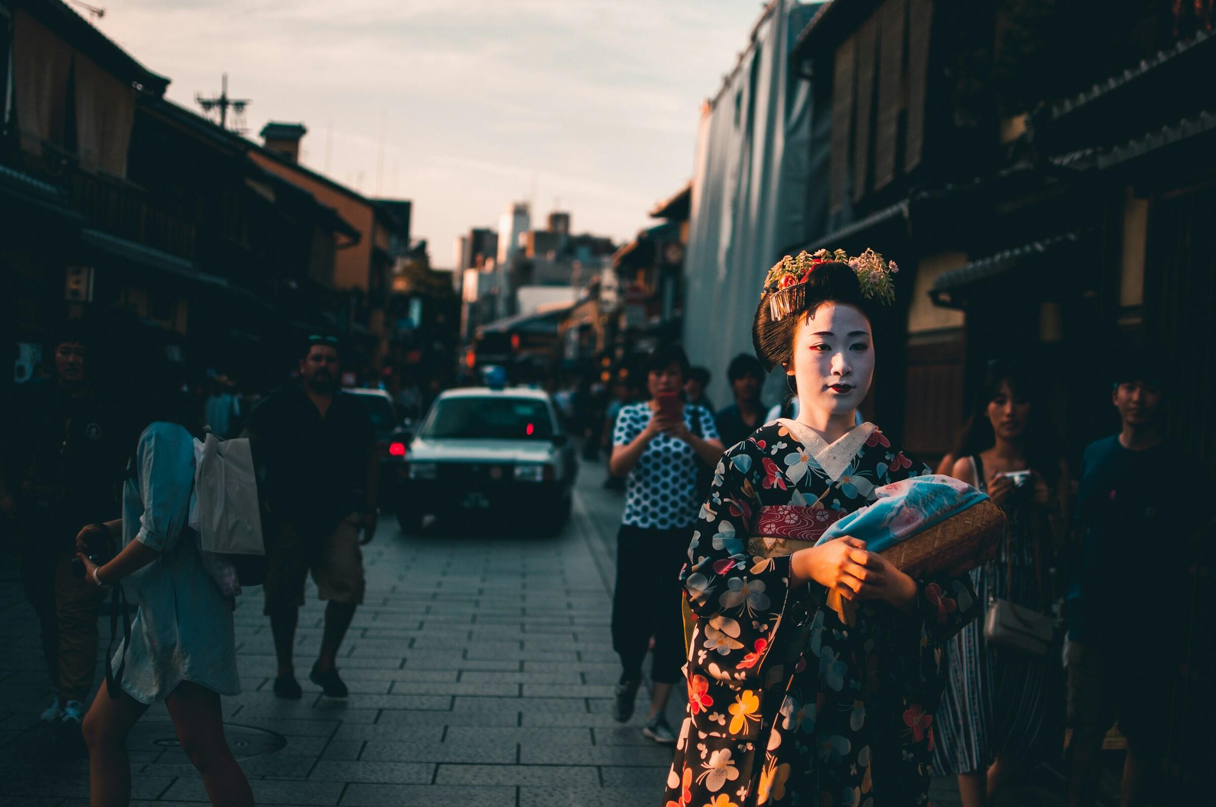 Eine Geisha läuft auf die Kamera zu auf einer Straße in Japan.