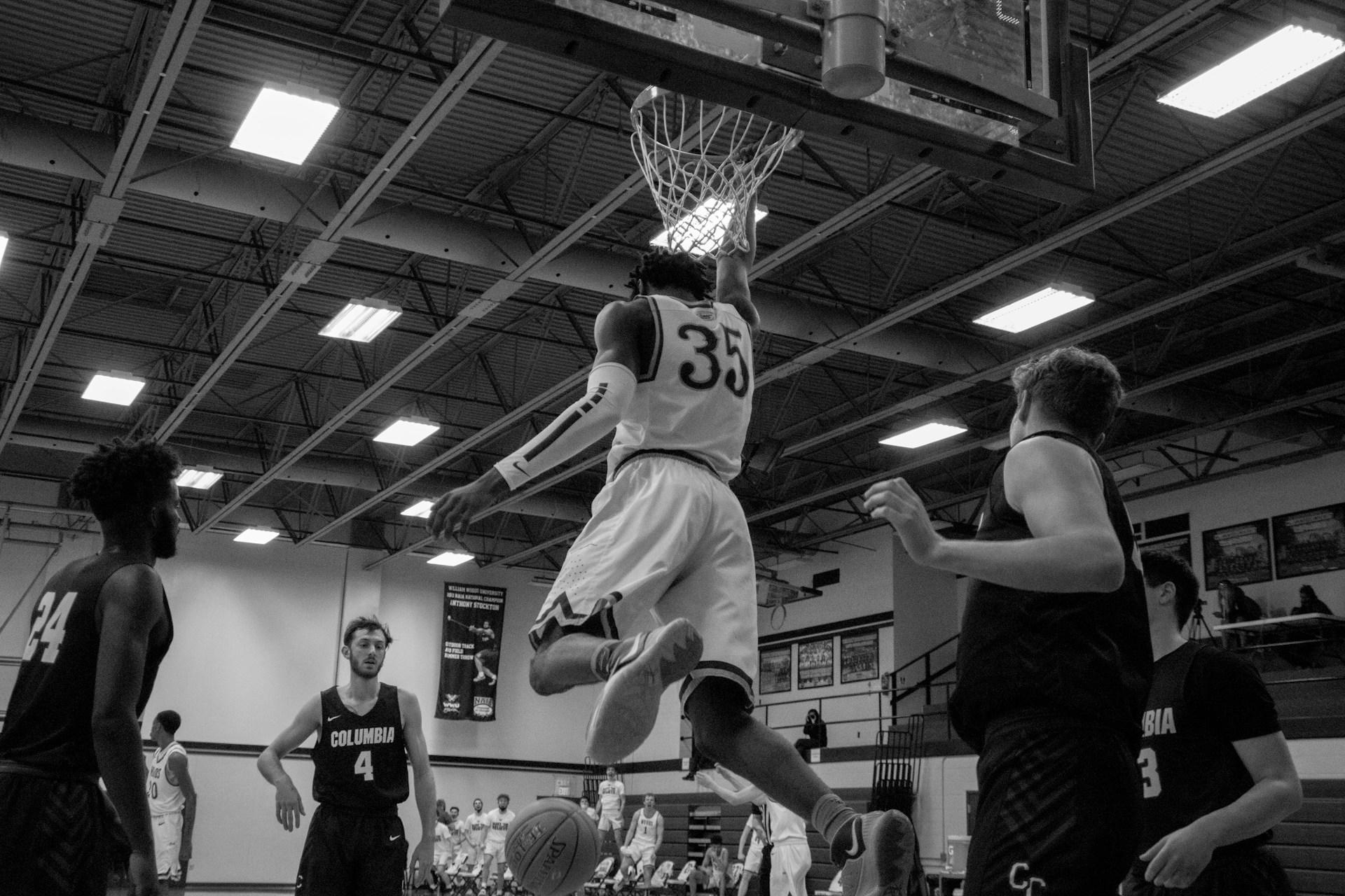 Basketballspieler spielen in einer Halle und einer hängt am Korb