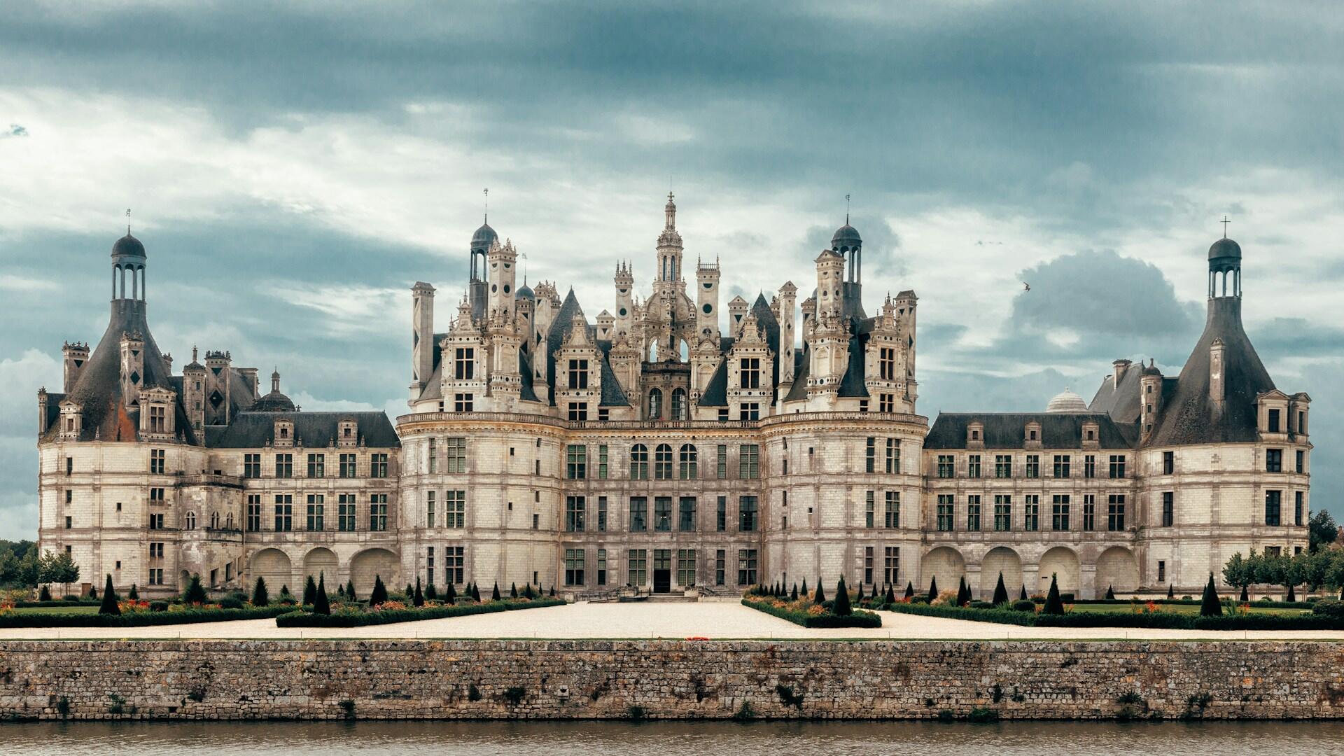 Schloss mit Türmen an Fluss.