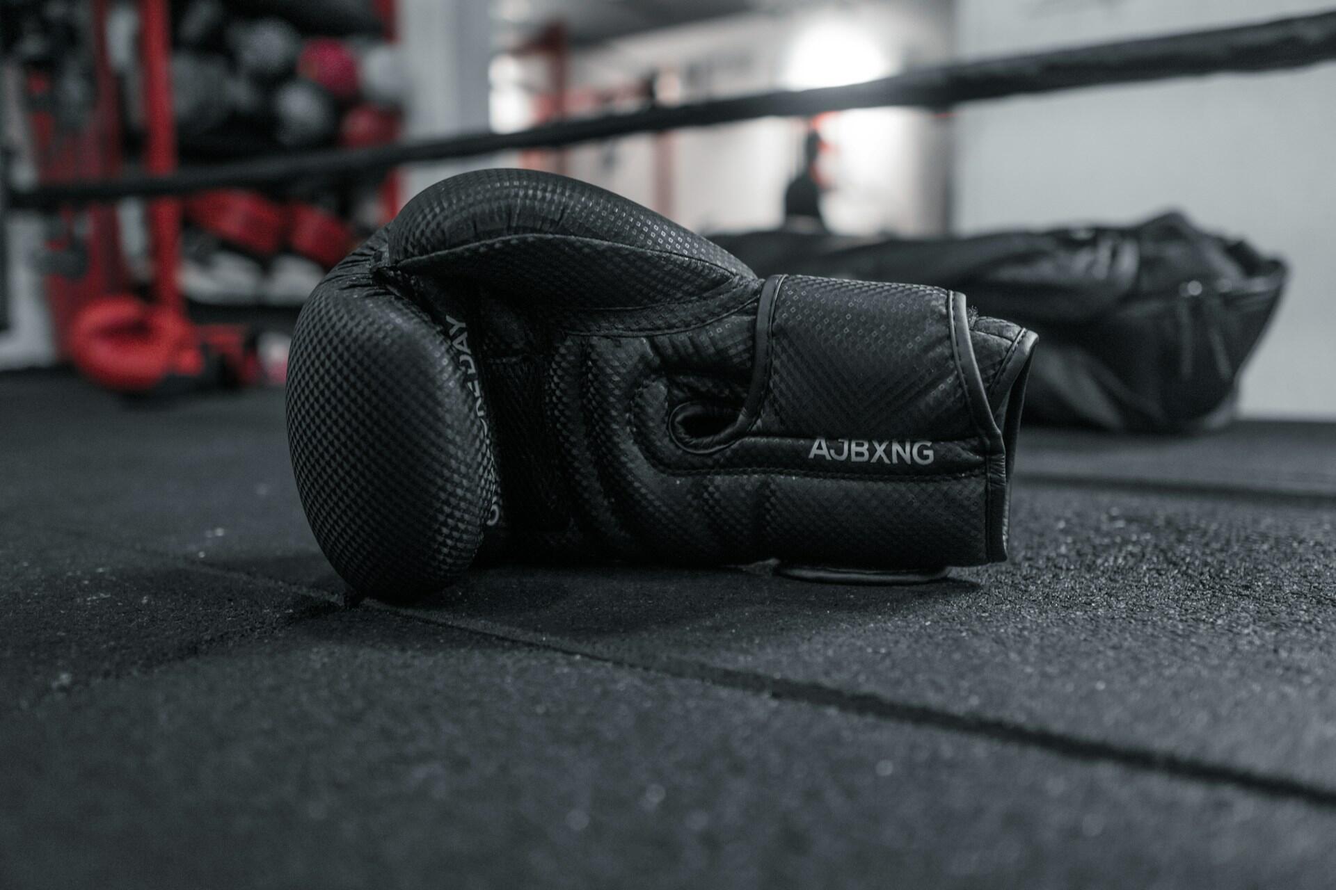 Schwarze Boxhandschuhe auf dem Boden liegend.