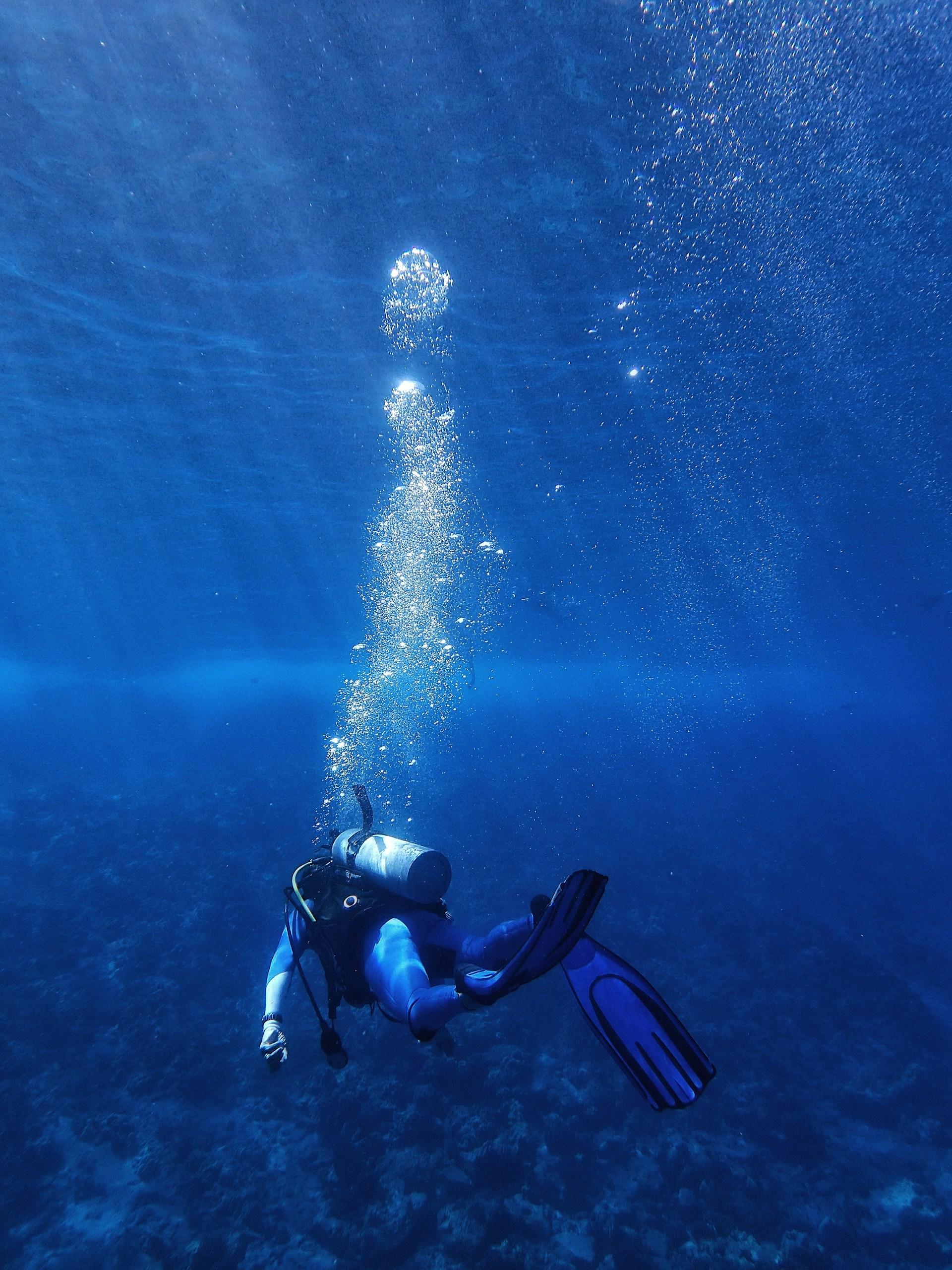 Taucher von hinten in blauem Wasser mit grosser Luftsäule