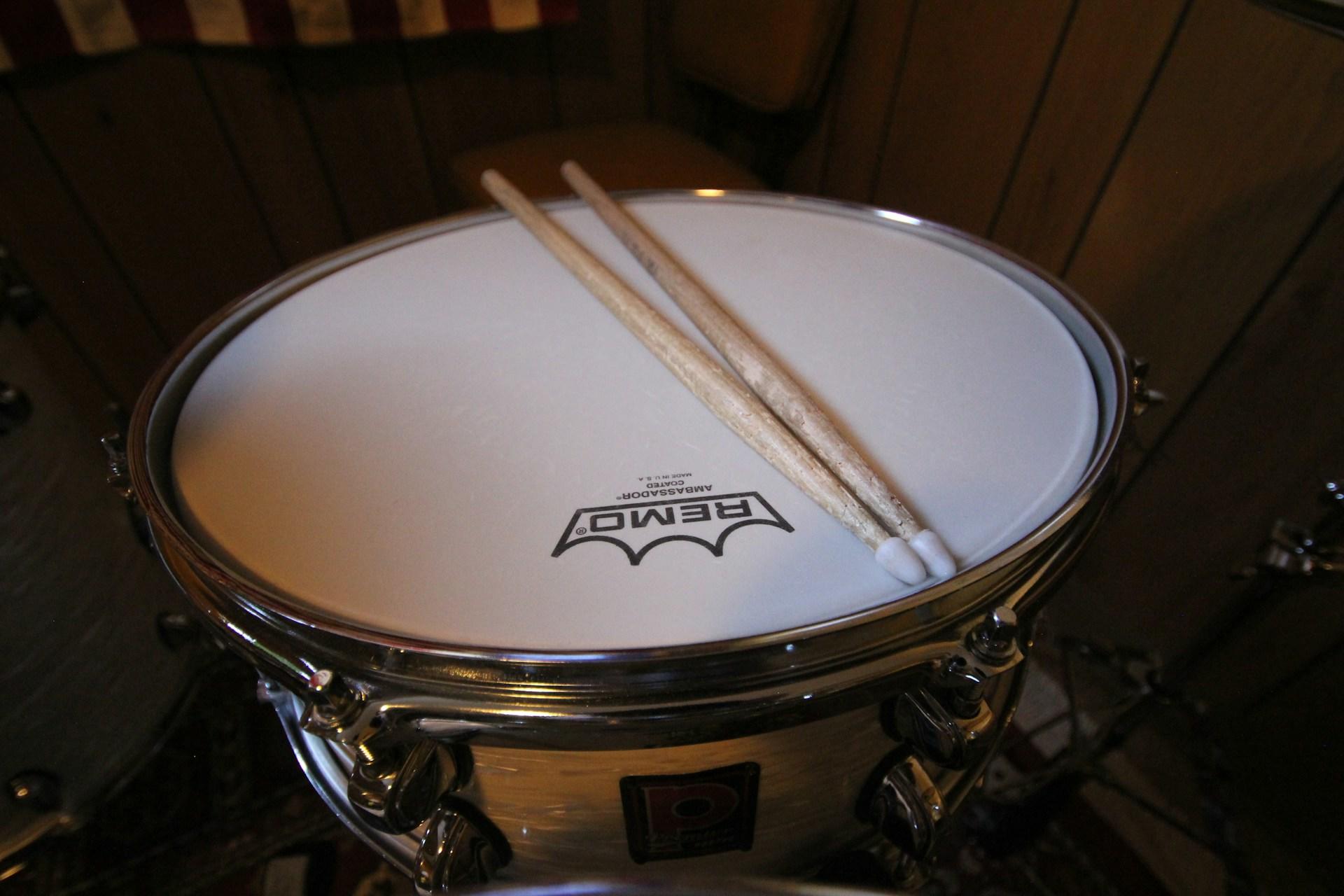Zwei Drumsticks liegen auf dem Fell einer Trommel