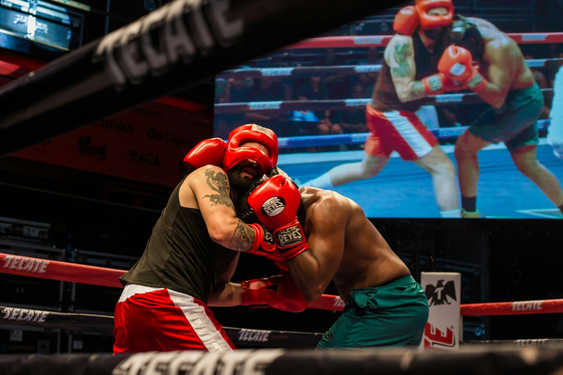 Zwei Boxer kämpfen vor Bildschirm in einem Boxring.