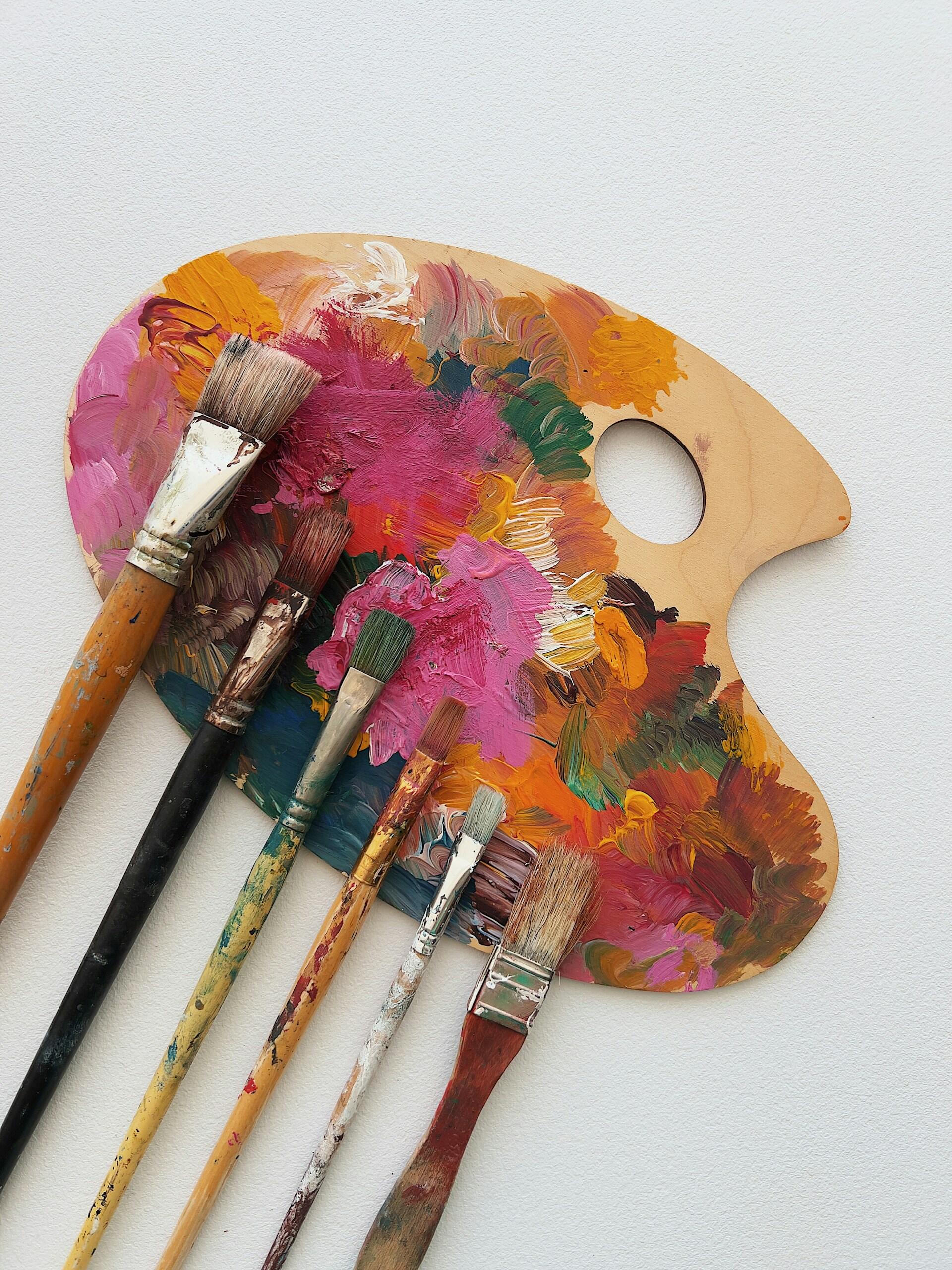 Einige Pinsel auf einer Malpalette voller Farbe.