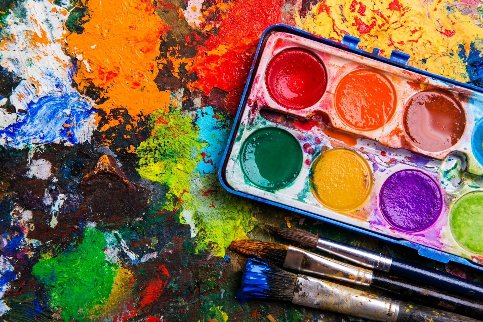 Eine Farbpallette und Pinsel auf bunten Klecksen