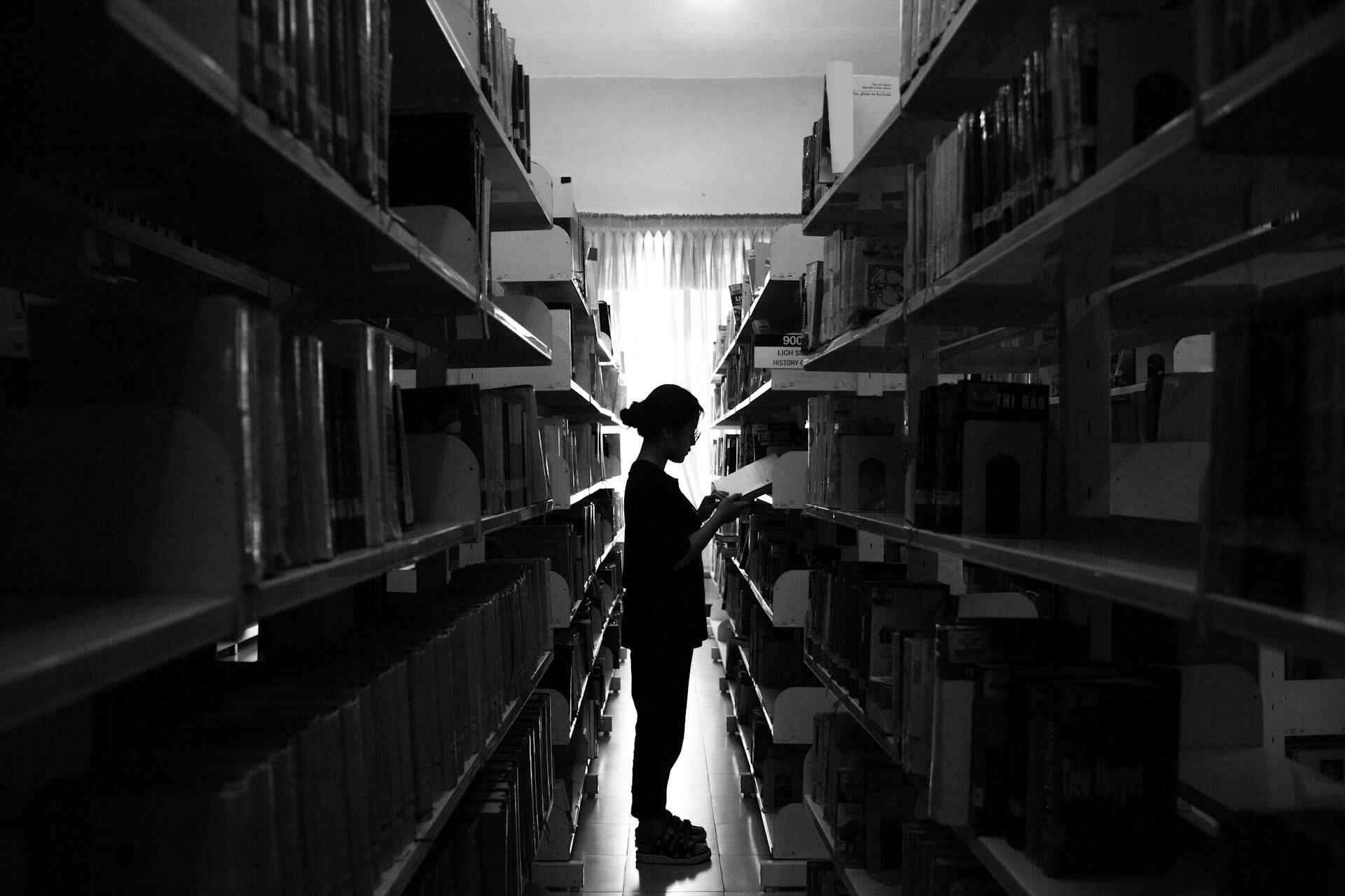 Eine PErson steht zwischen Bücherregalen