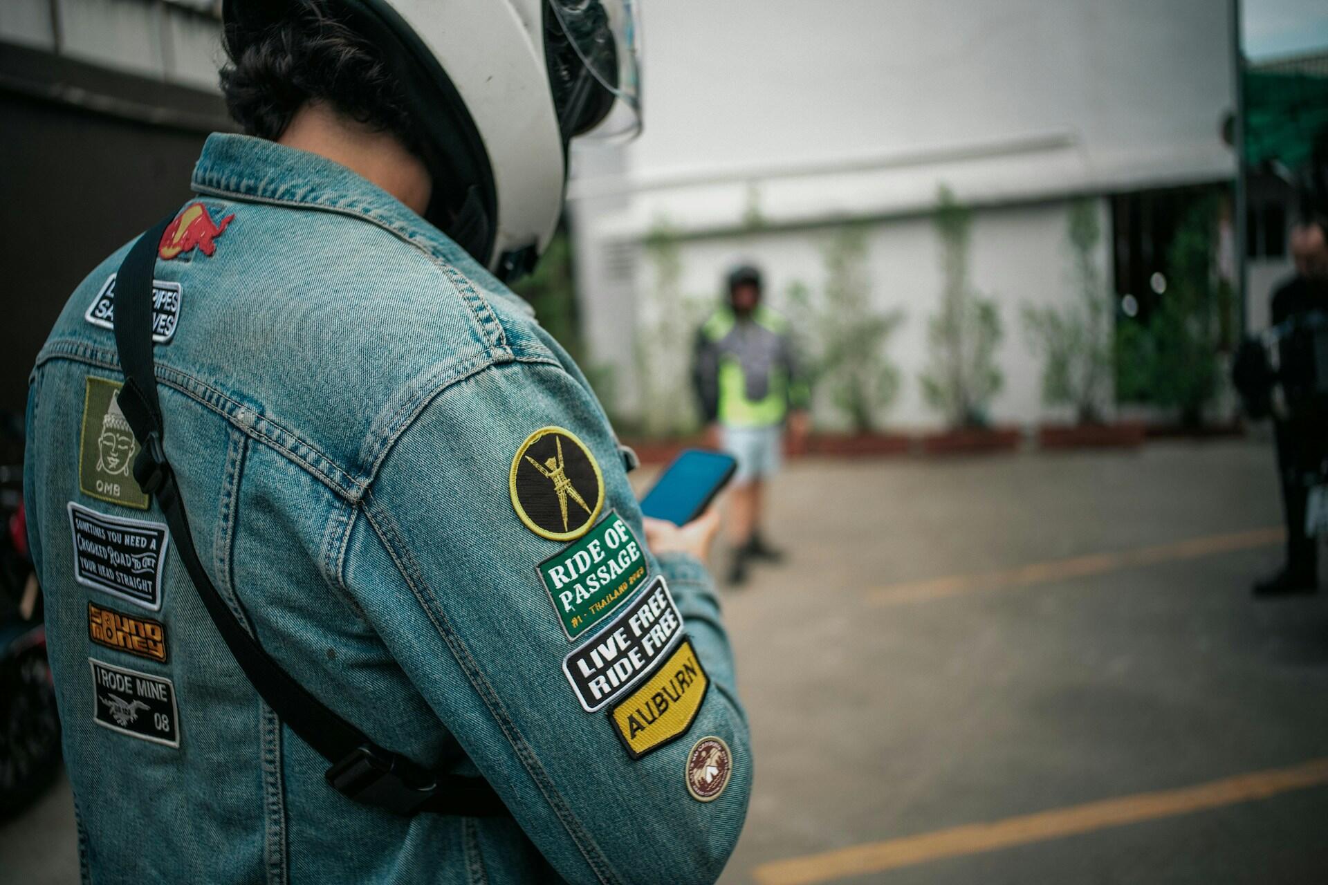 Ein Motorradfahrer mit Jeansjacke auf der viele Patches aufgebügelt sind.