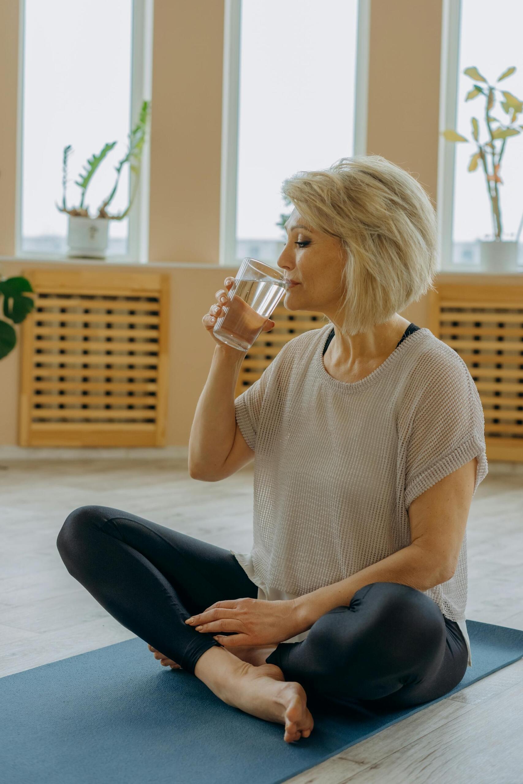 Frau beim Yoga trinkt ein Glas Wasser