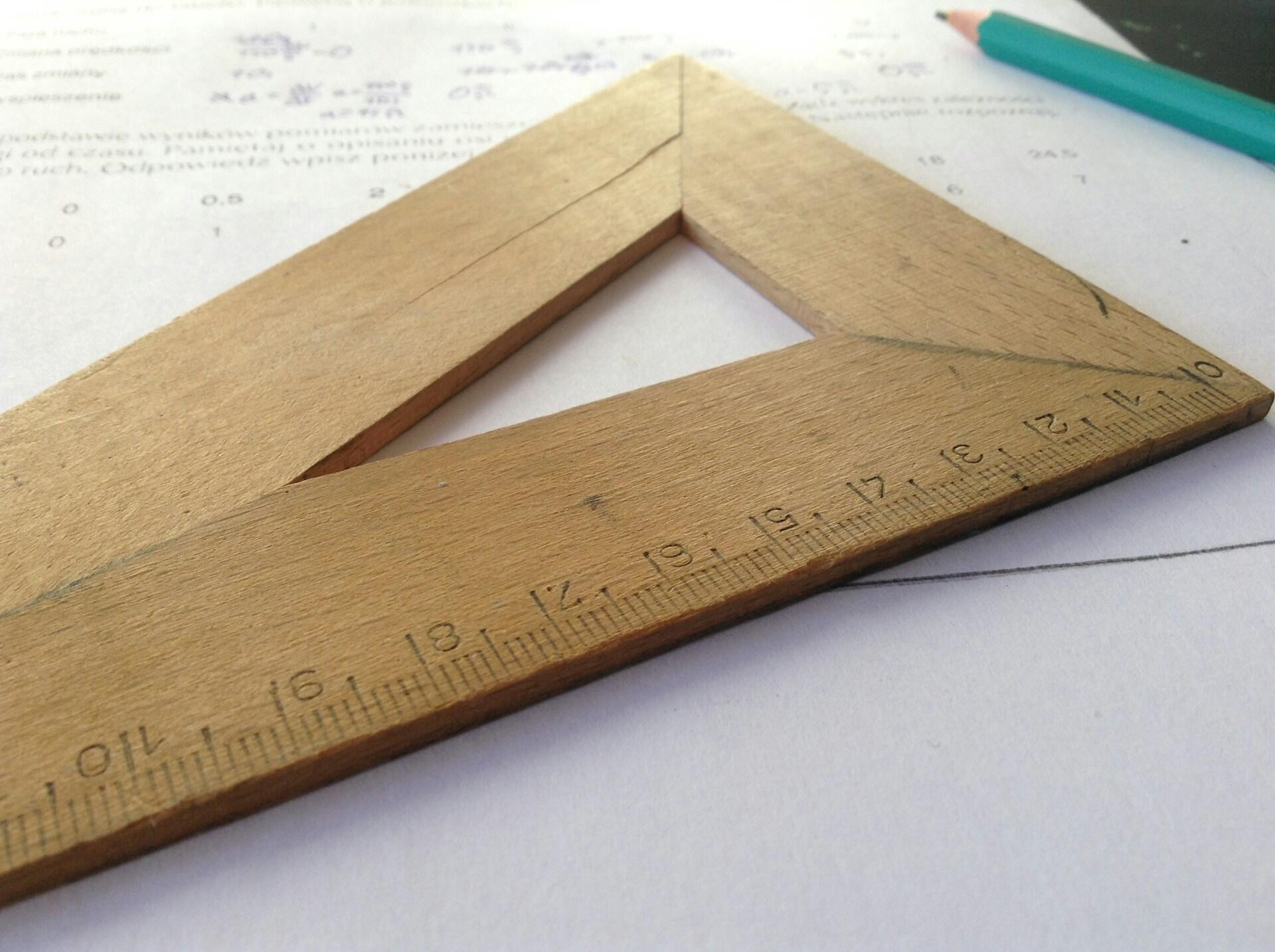 Geodreieck aus Holz auf Blatt neben Stift.