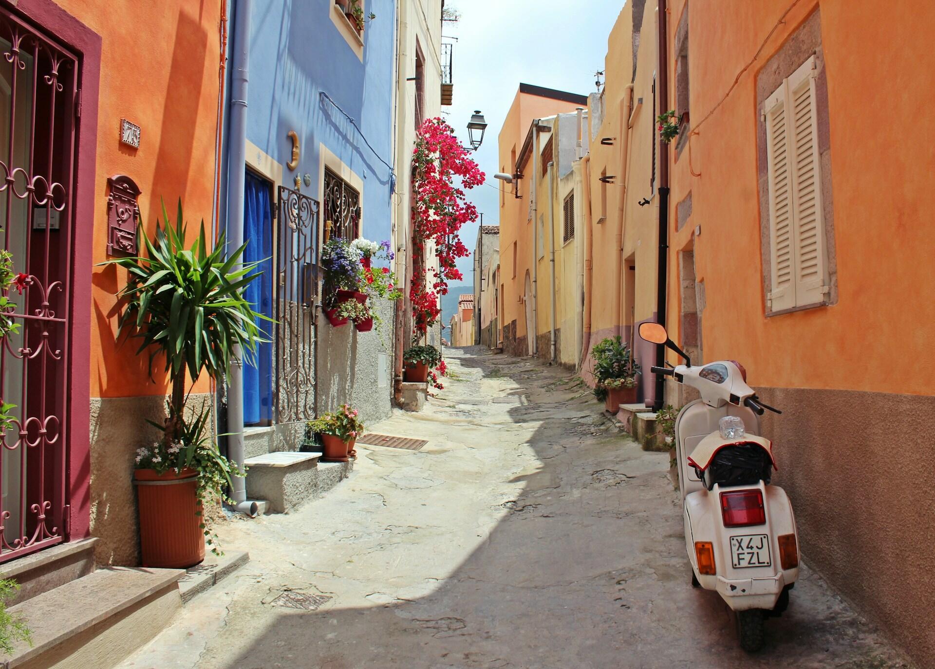Gasse mit bunten Hauswänden und Motorroller an der Wand.