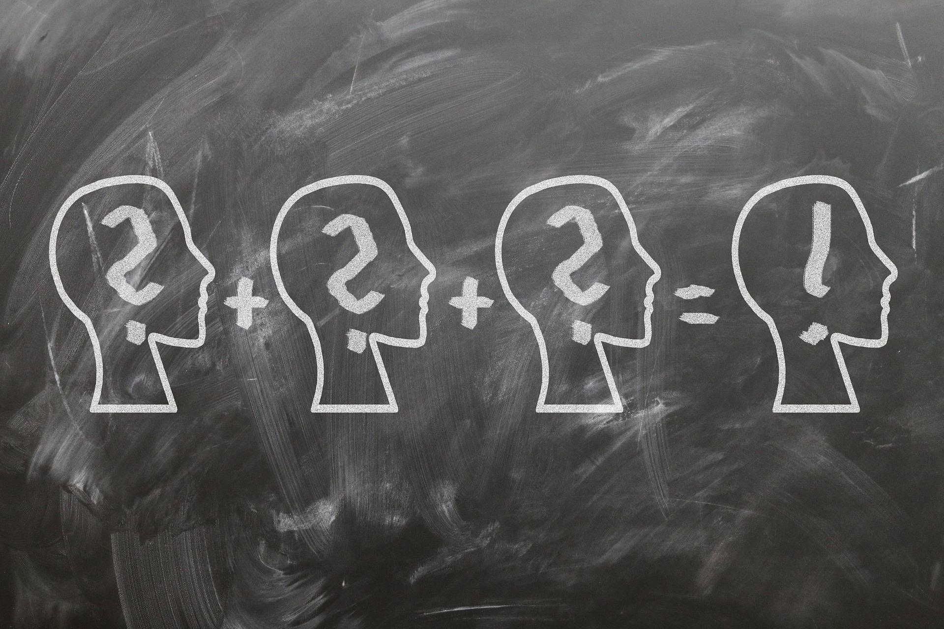 Auf eine Tafel gezeichnete Köpfe mit Ausrufezeichen und Fragezeichen