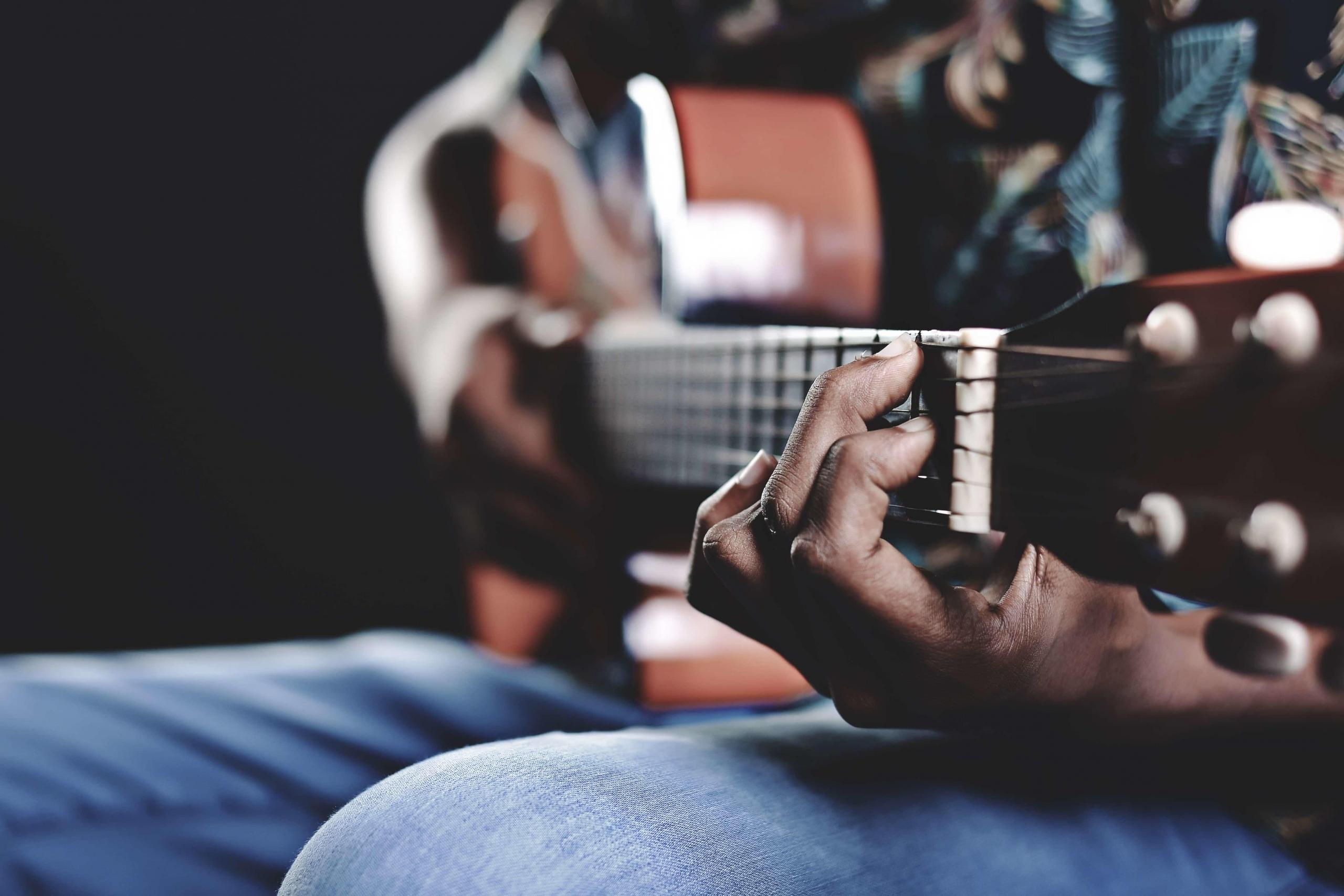 Die richtige Haltung der Gitarre: Rechtshänder greifen die Saiten mit der linken Hand und schlagen sie mit der rechten Hand an.