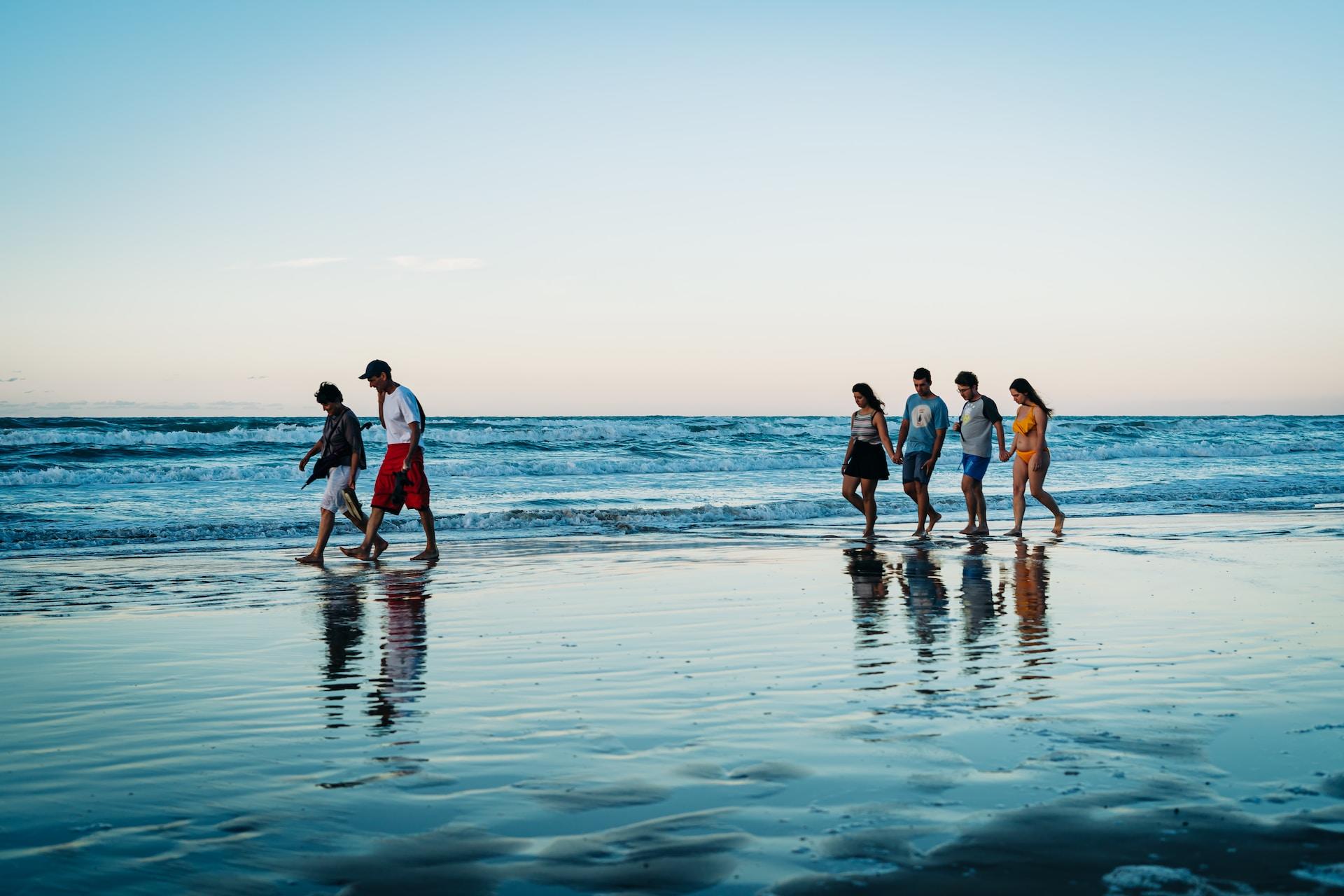 Lerne Leute in Italien kennen wie diese jungen Menschen die am Abend einen Strand entlang spazieren.