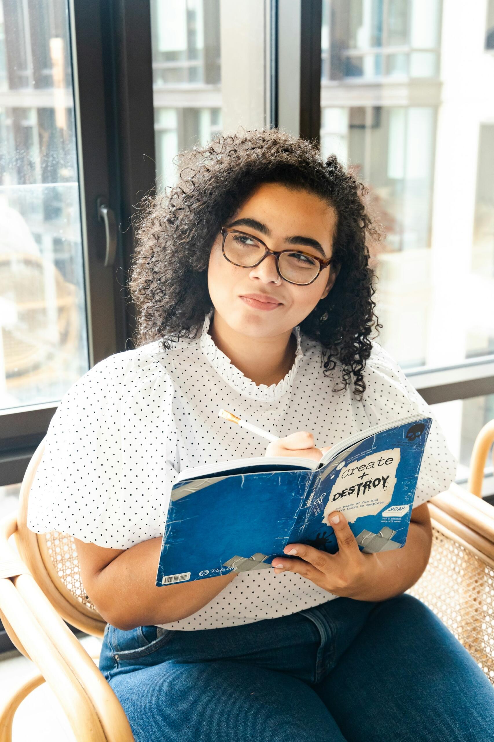 Eine junge Frau liest ein Buch mit einem nachdenkllichen Blick.