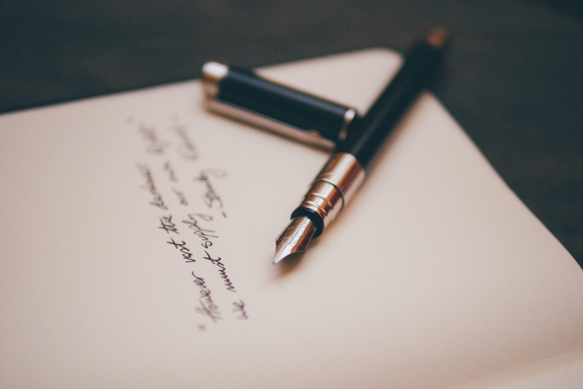 Füller liegt auf Papier mit Schrift drauf.