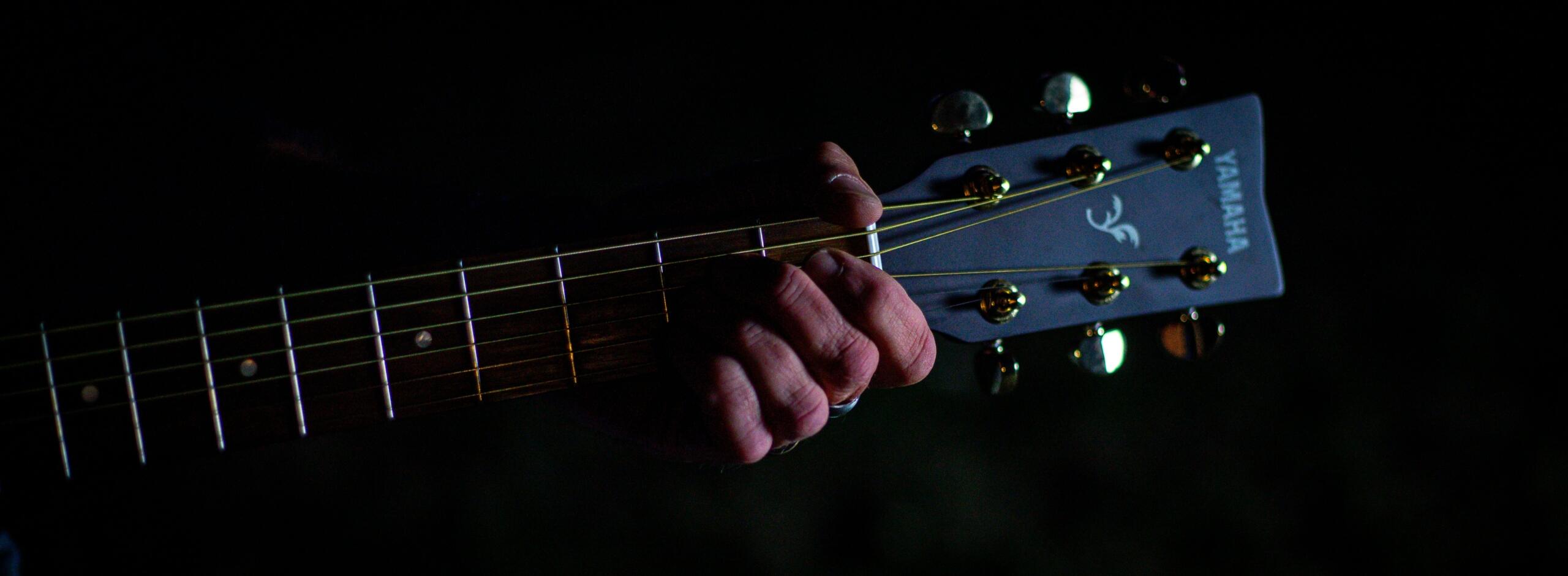 Hand auf dem Griffbrett einer Yamaha Gitarre