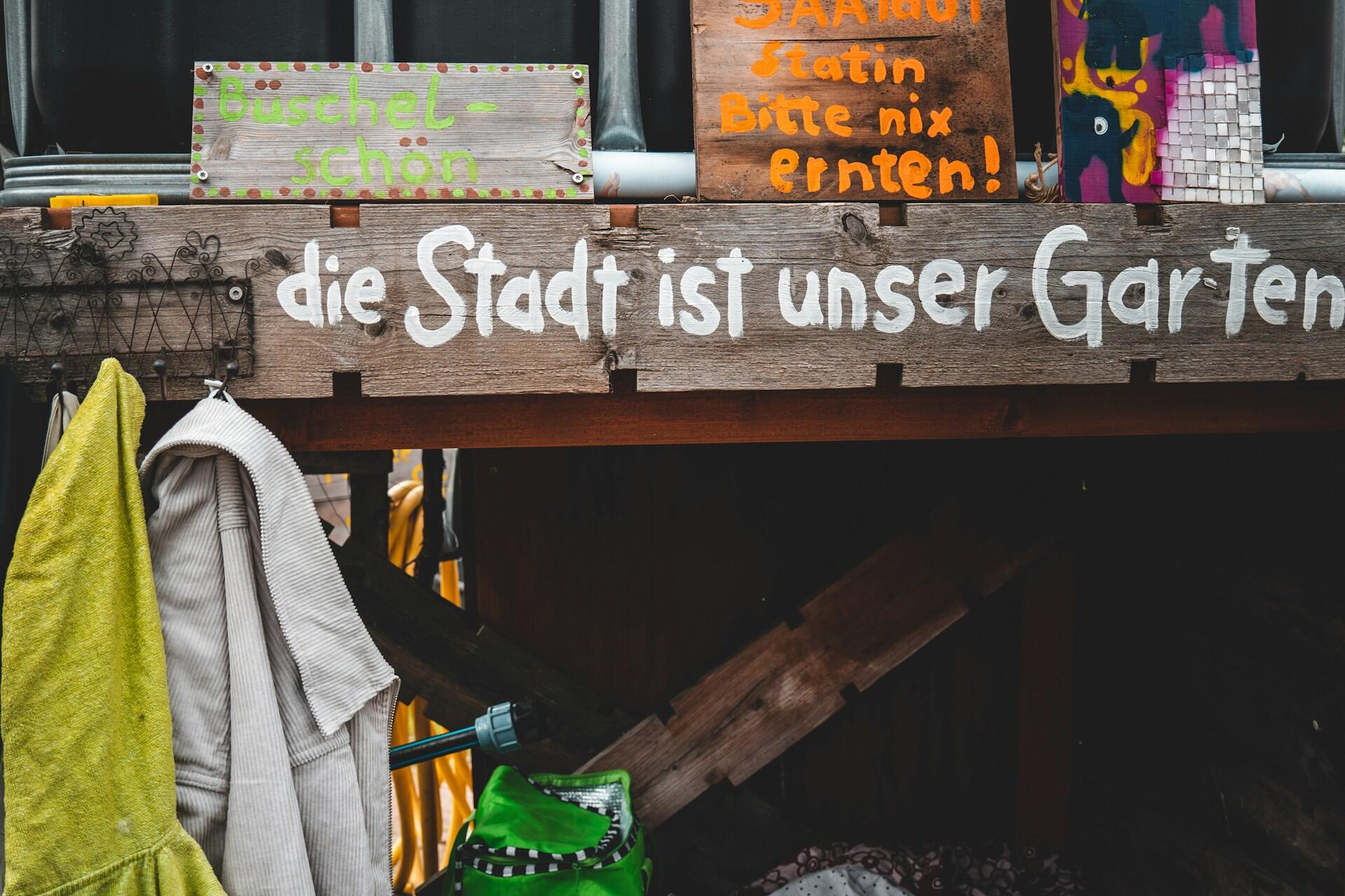 Holzbrett mit weißer Schrift und Jacken dran.
