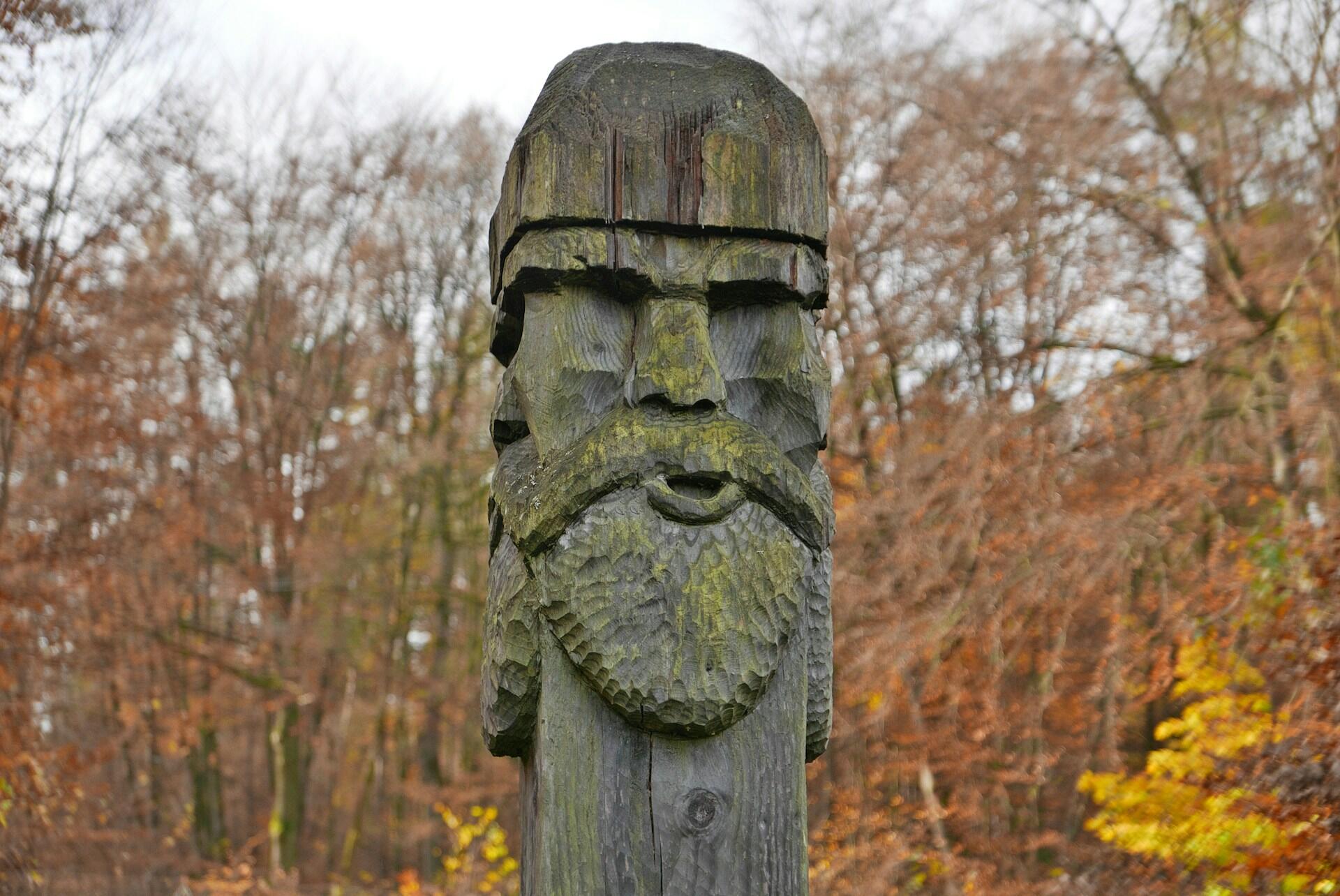 Holzfigur von Mann mit Bart im Wald.