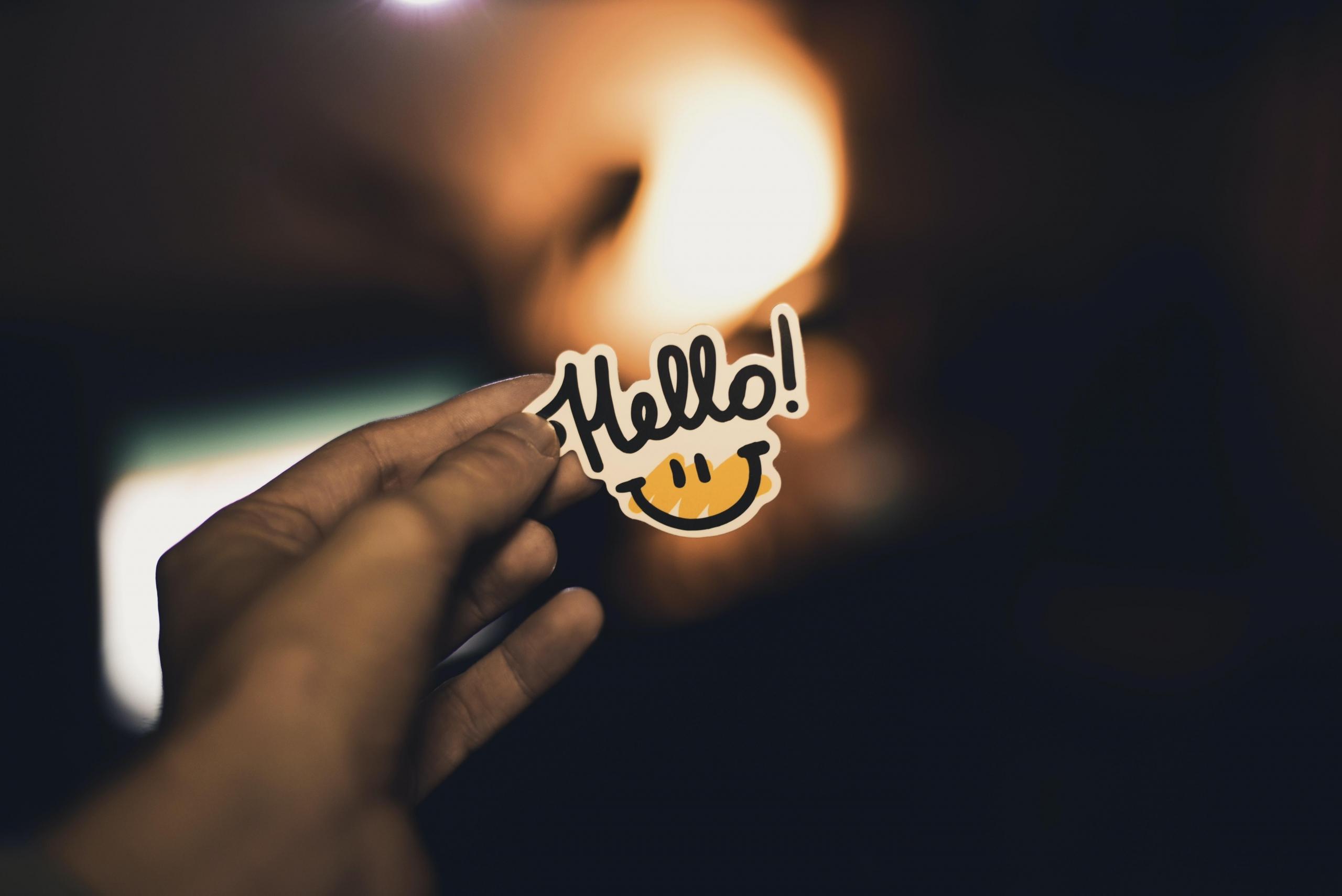 Hand hält Sticker mit Smiley.