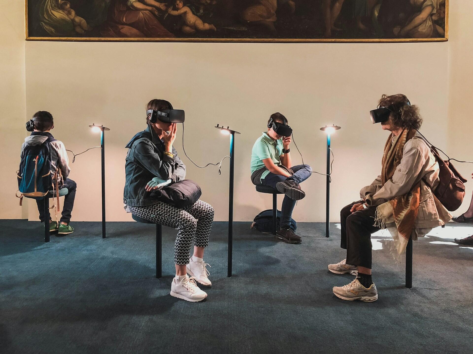 Bier Menschen sitzen mit VR-Brillen auf Hockern in einem Raum.
