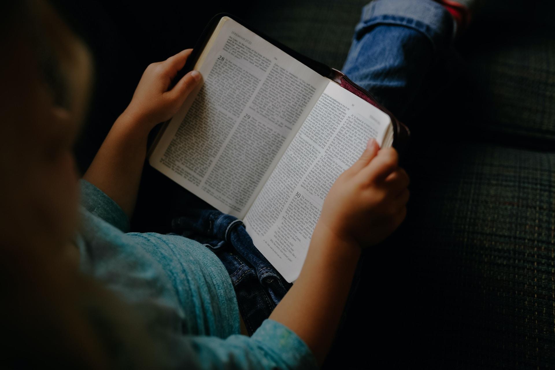 Aufgeklapptes Buch in den Händen einer Person.