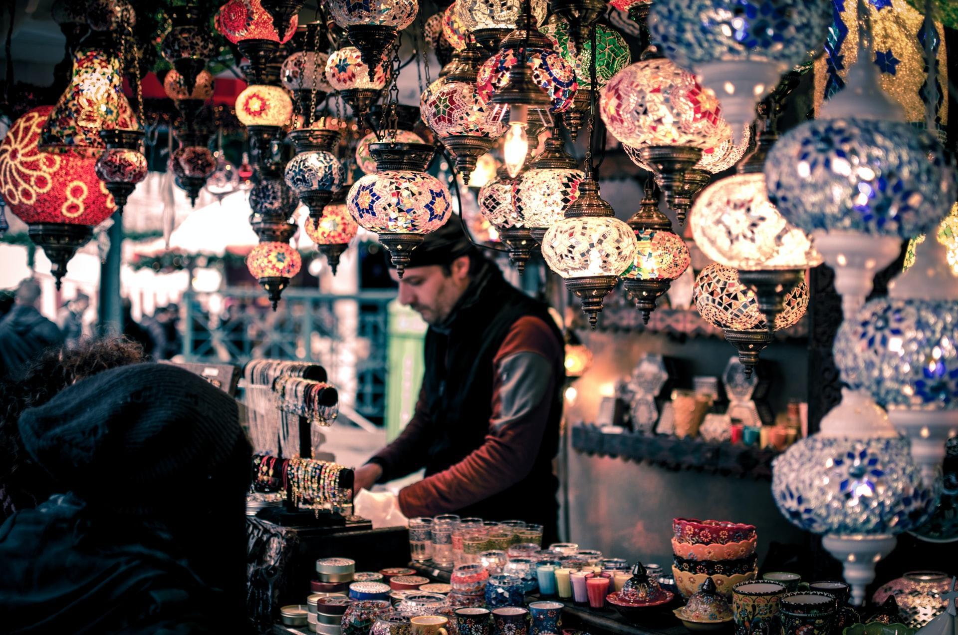 Marktstand mit bunten Lampen und Mann in der Mitte.