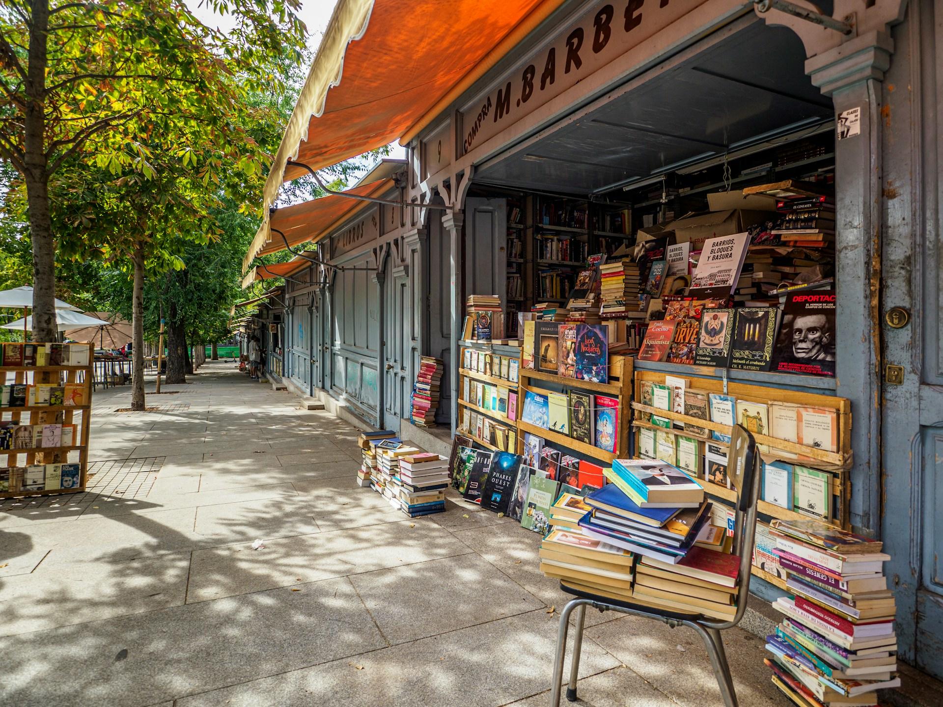 Openair Antiquariat mit spanischen Büchern in Madrid im Sommer mit grünen Bäumen im Hintergrund.