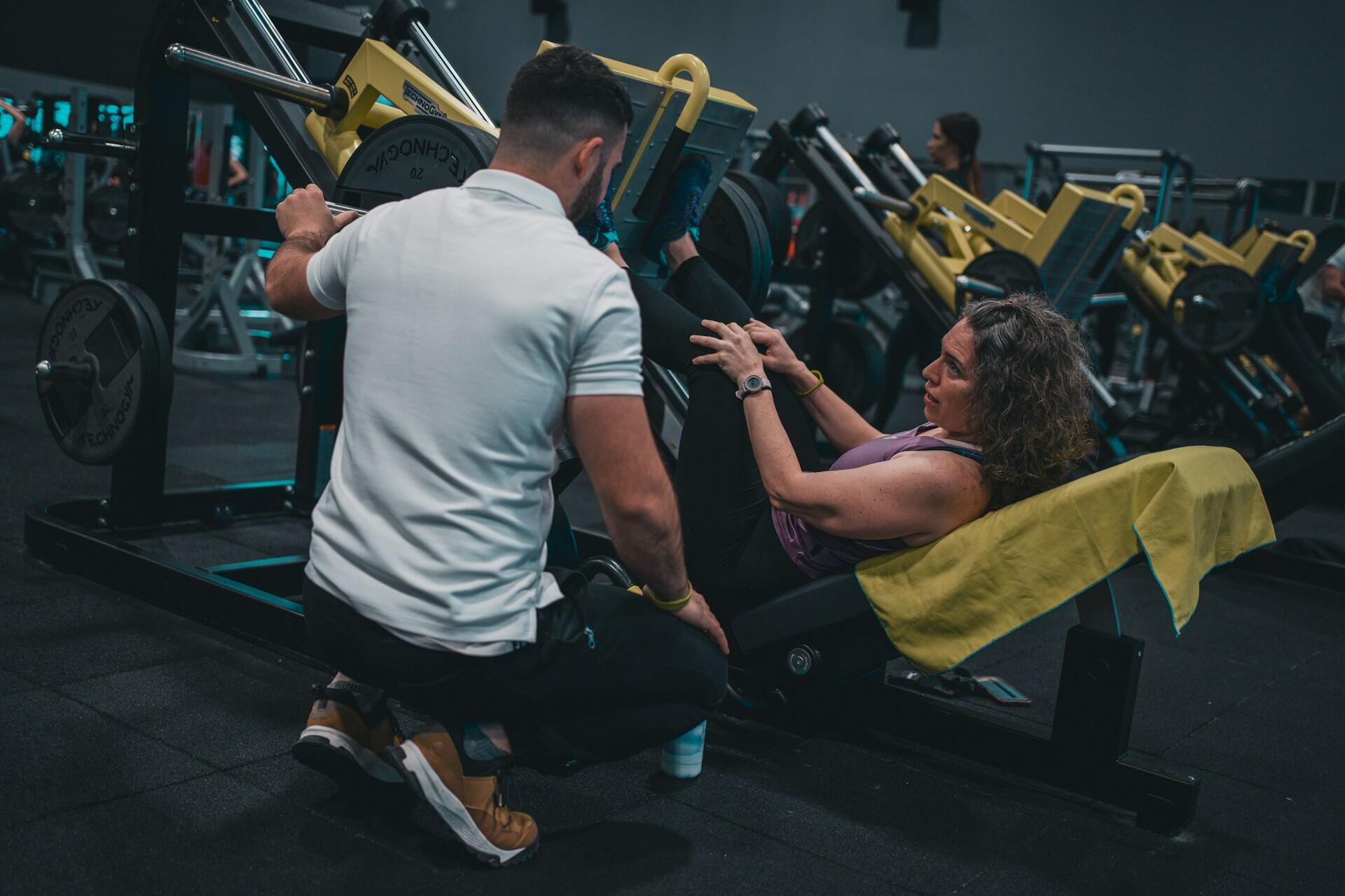 Frau an der Beinpresse mit Personal Trainer