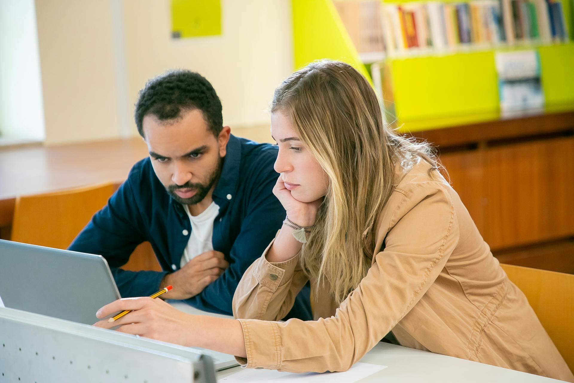 Eine Frau und ein Mann schauen auf einen Laptop
