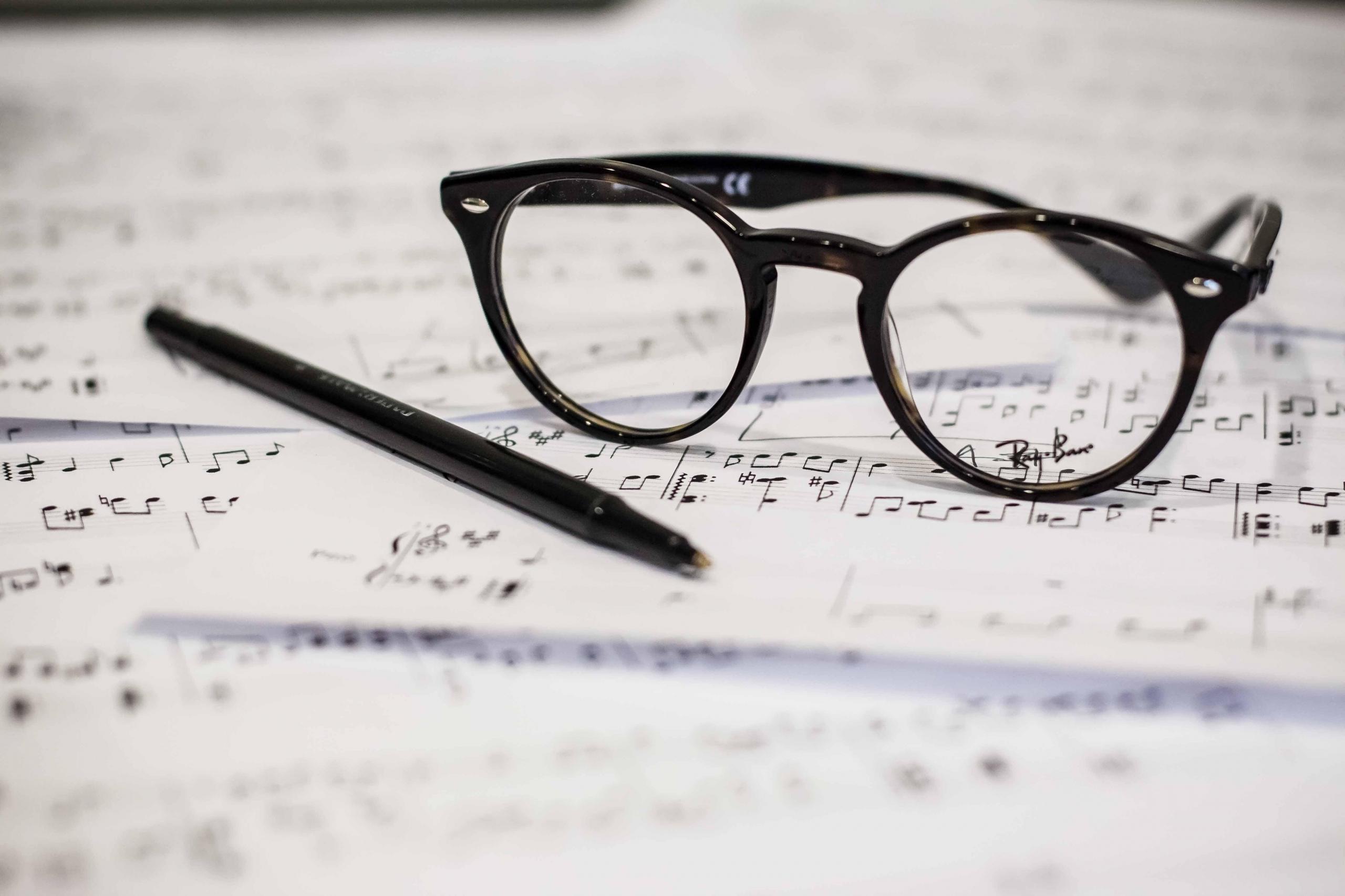 eine Brille und ein Stift auf einem Notenblatt