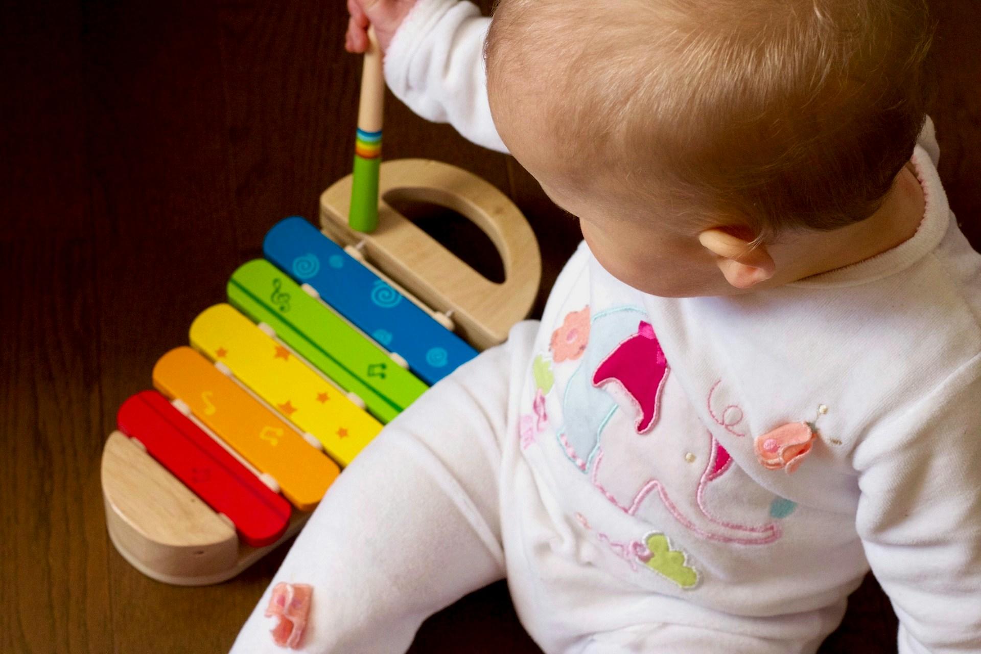 Kleinkind mit Musikinstrument aus Holz.
